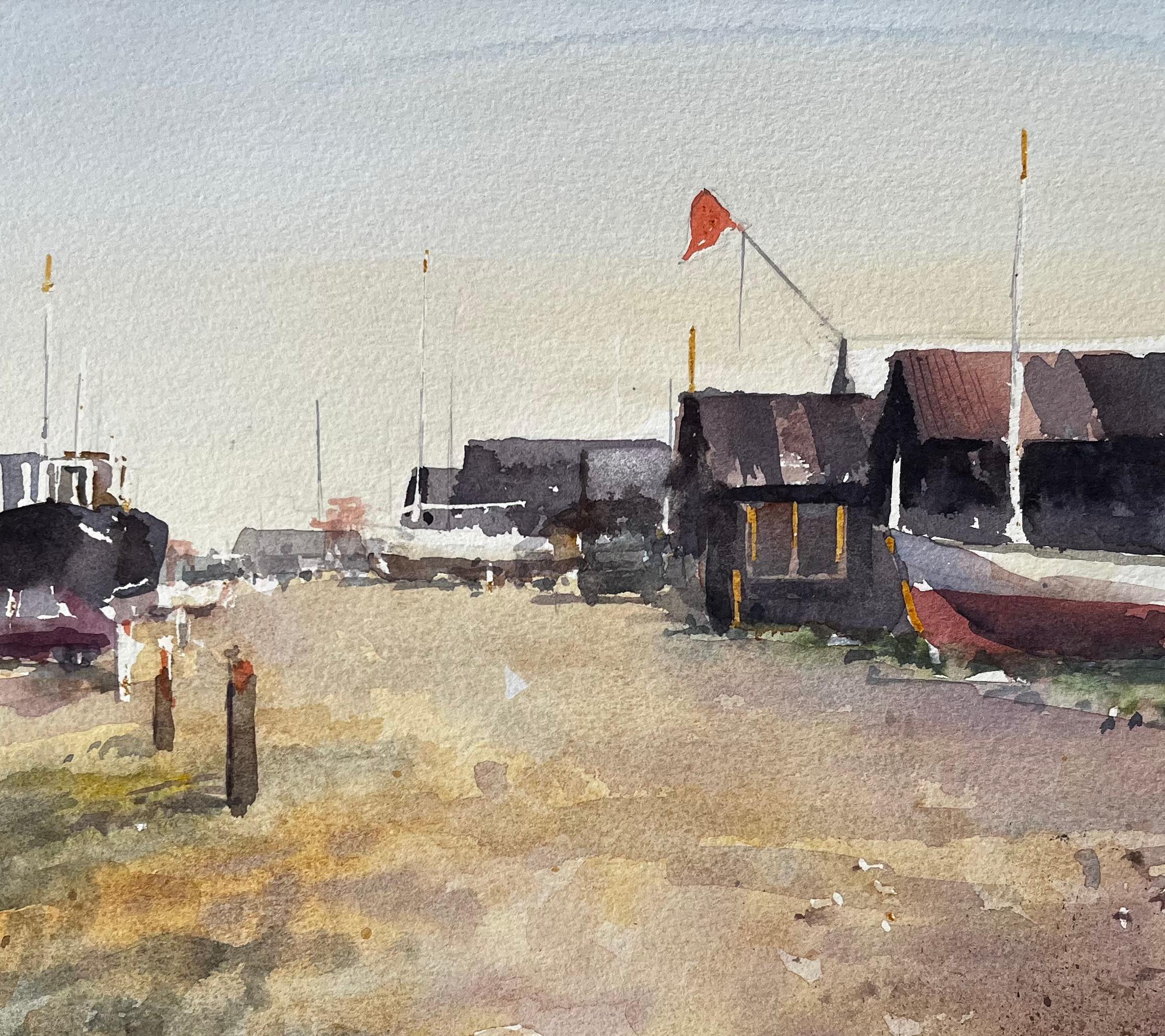 Küstenwerft mit Fischerhütten, gestrandeten Booten und roter Flagge Aquarellszene (Braun), Landscape Art, von Anthony Herbert