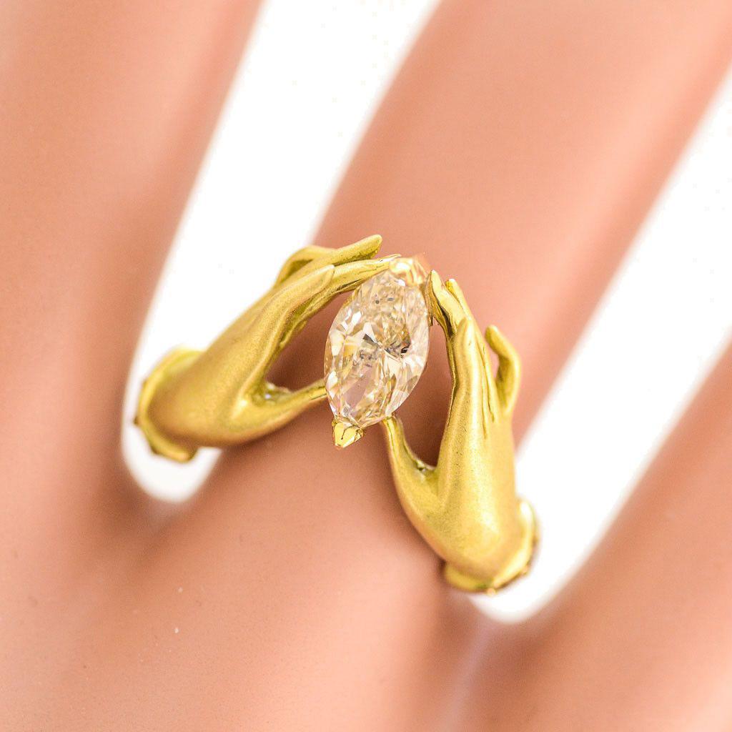 Solid 18K Yellow Gold Natural Marquise Diamond Adorned Hands Ring by Anthony Lent in Excellent Condition! This unique ring is a size 5 1/4, and weighs about 7.2 grams. This ring has 10 round diamonds, approximately .005CTTW, and the center marquise