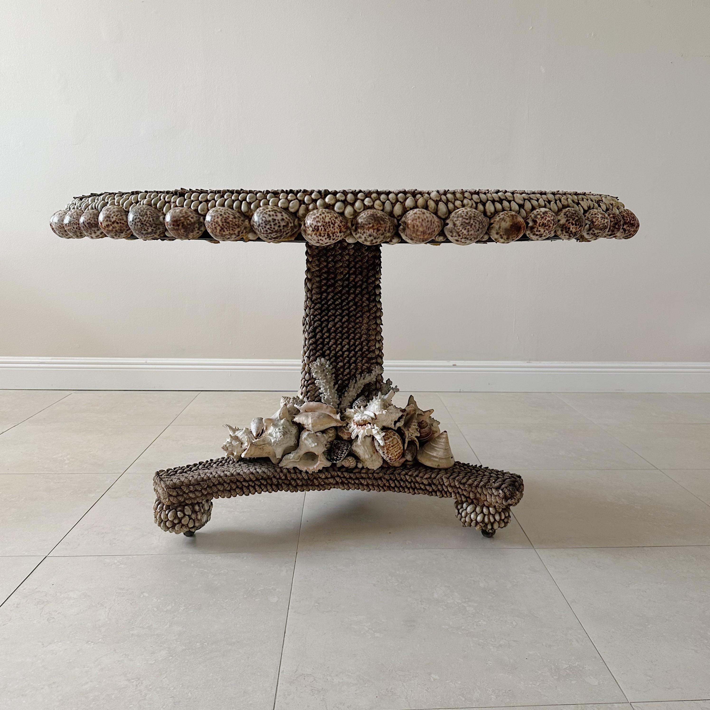 An exquisite center table meticulously handcrafted by the renowned artist Anthony Redmile, born in 1940. This masterpiece boasts a surface adorned with a stunning assortment of molluscan and cowrie shells. Atop the table rests a signature silvered