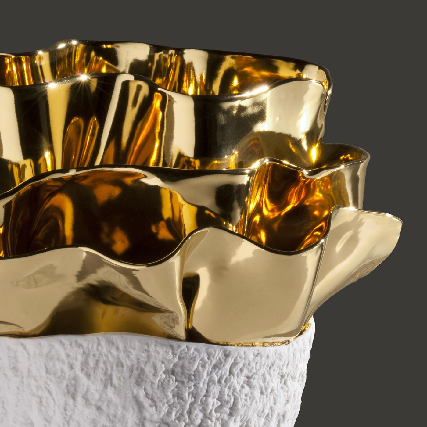 The particular elliptical shape and textured surface resembling hammering, are the result of a meticulous study on the microscopic magnification of a seed. This precious vase in glazed porcelain is decorated with gold 23-karat, applied by expert
