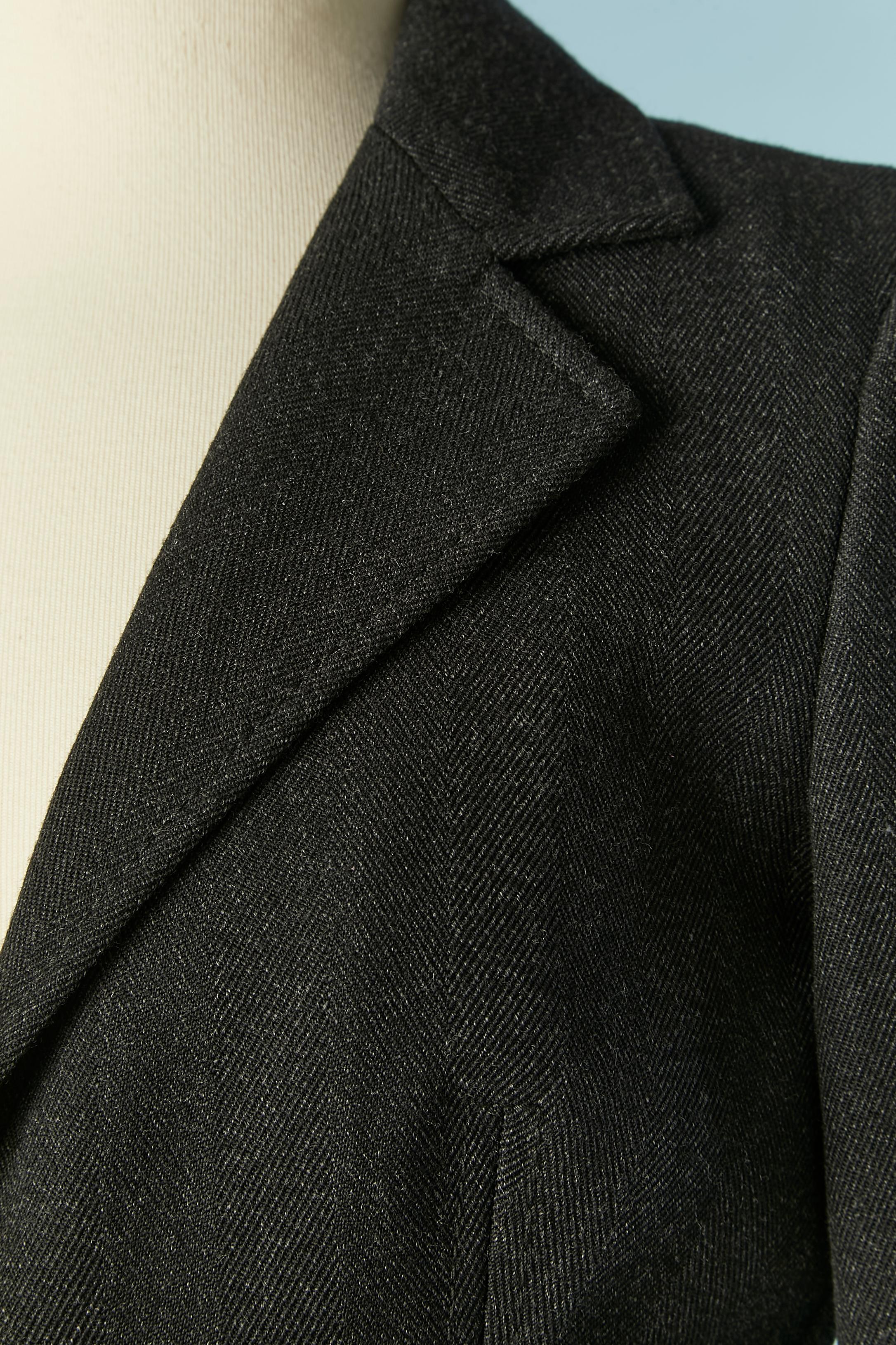 Anthracite grey wool chevron skirt suit. Printed lining inside the jacket and skirt, the fabric composition tag has been cut but it's probably acetate. Shoulder-pad. Button and buttonhole closure on the middle front + buttons on the cuffs ( no