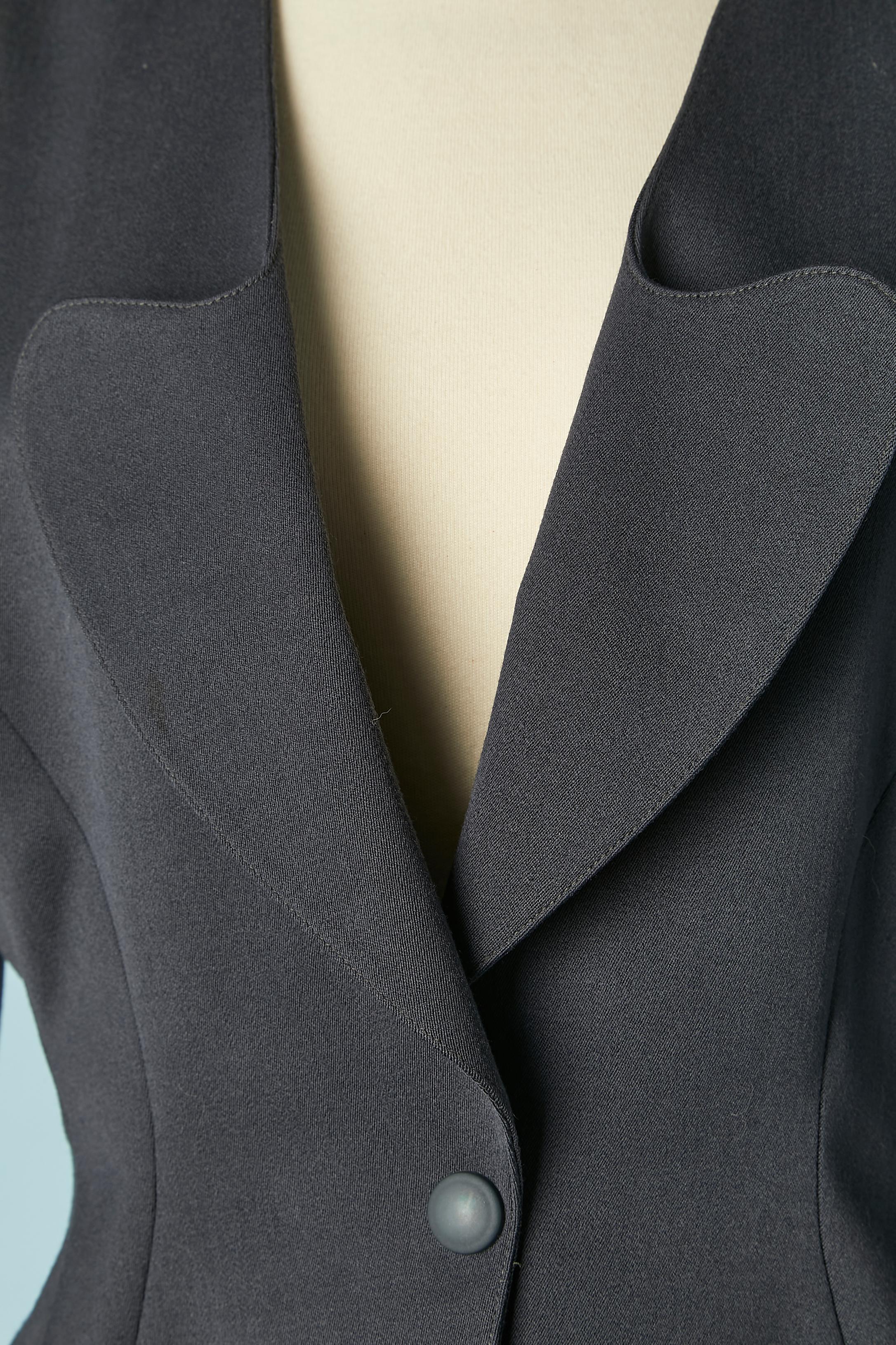 Combinaison jupe en laine gris anthracite. Doublure : 60% acétate, 40% cupro. Pad d'épaule. Découpage. Une fermeture à bouton-pression au milieu du devant. 
TAILLE 40 (Fr) 10 (Us) pour la veste et 38 (Fr) 8 (US) M pour la jupe 