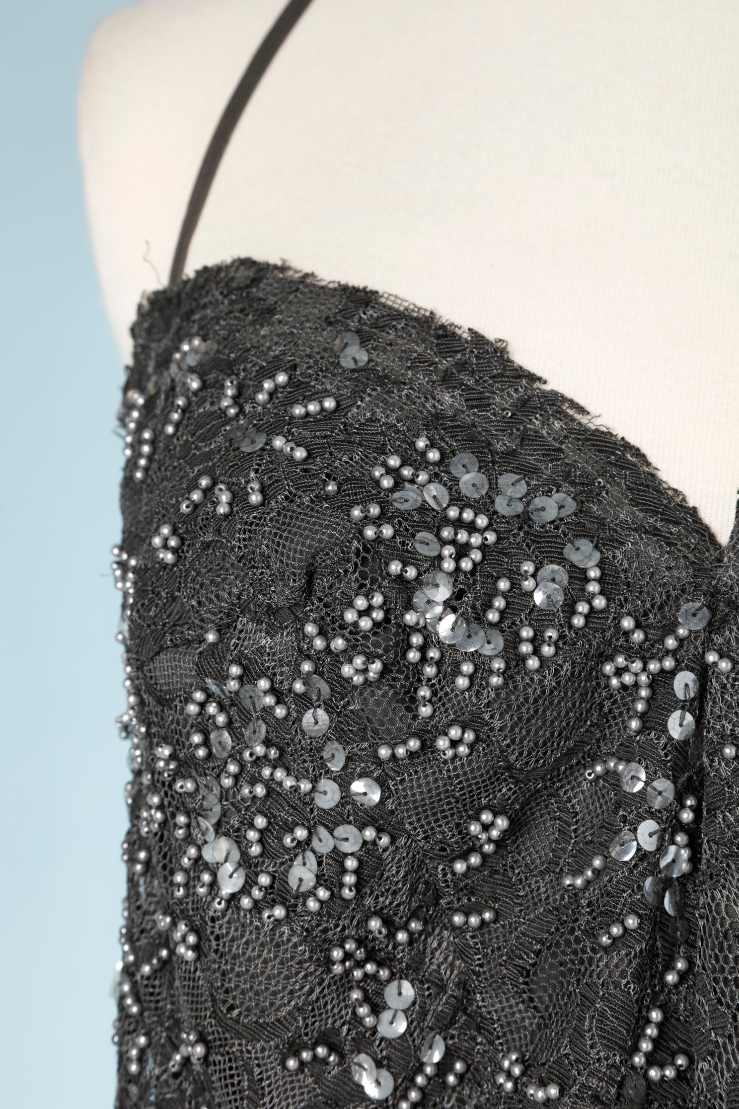 Top in pizzo antracite con paillettes e perline. L'etichetta della composizione del tessuto è stata tagliata ma il pizzo è probabilmente in poliestere e la fodera in cotone. 
Chiusura con zip al centro della schiena. Bordo inferiore tagliato a vivo.