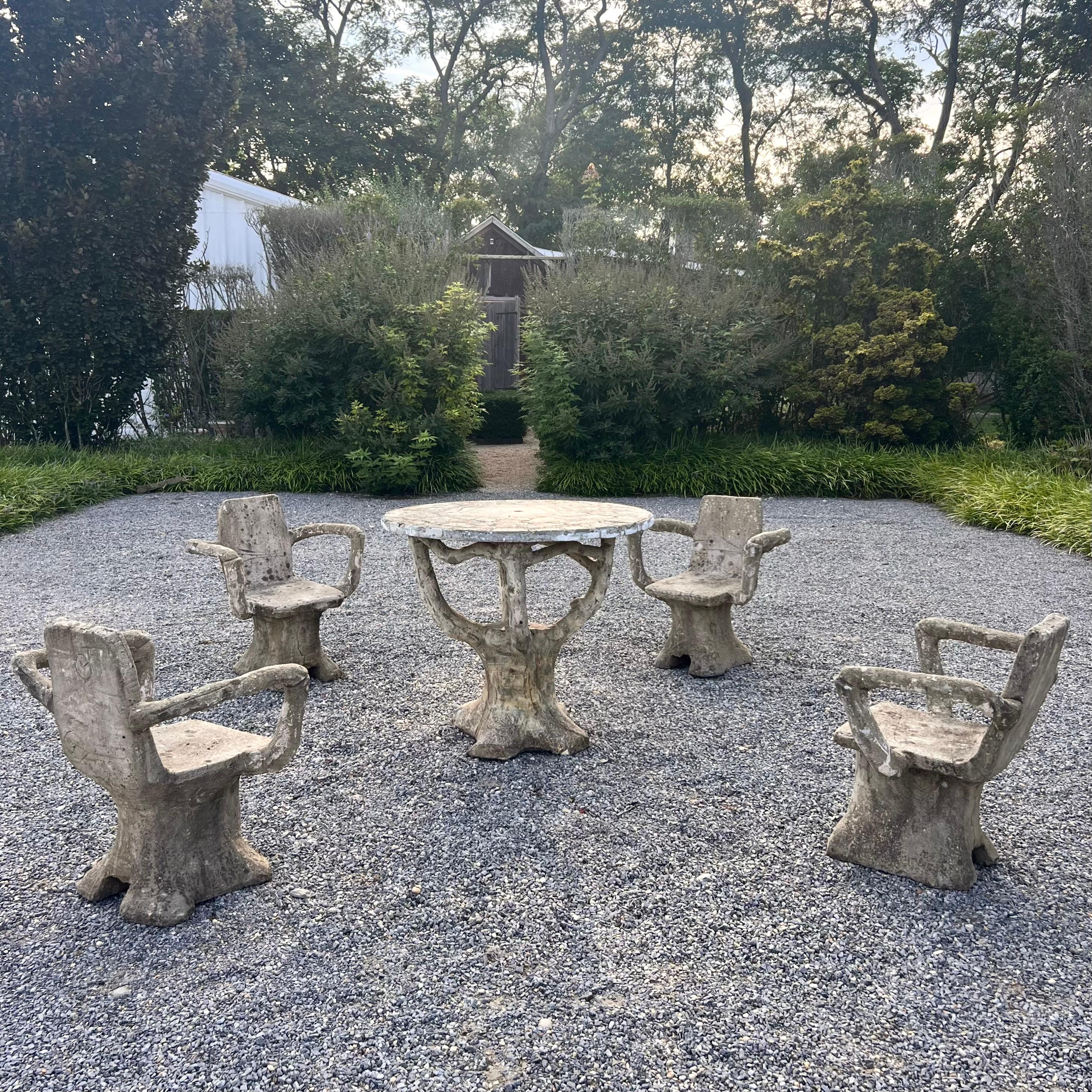 Substantial faux-bois concrete table and stools from France, made in the 1950s. 4 chairs and one table included in this set. Anthropomorphic style to arms of chair. Legs and table base resemble tree trunks and branches with great realistic design.