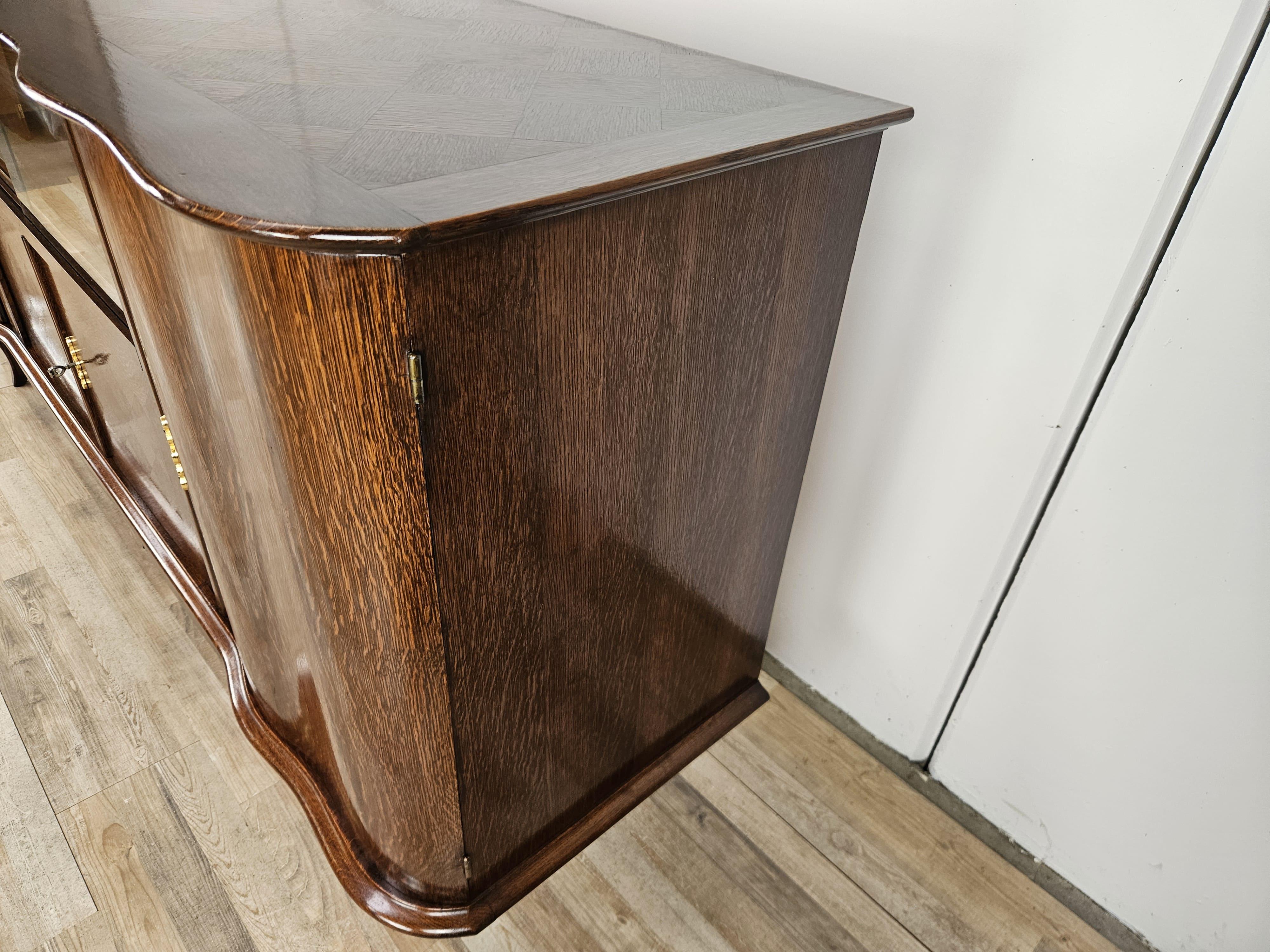 1950s Art Deco oak sideboard with a distinctive checkerboard shape play on the main top.

The cabinet has two side doors equipped with an internal shelf and a small drawer, in the center is a compartment with ample storage space, and in the central
