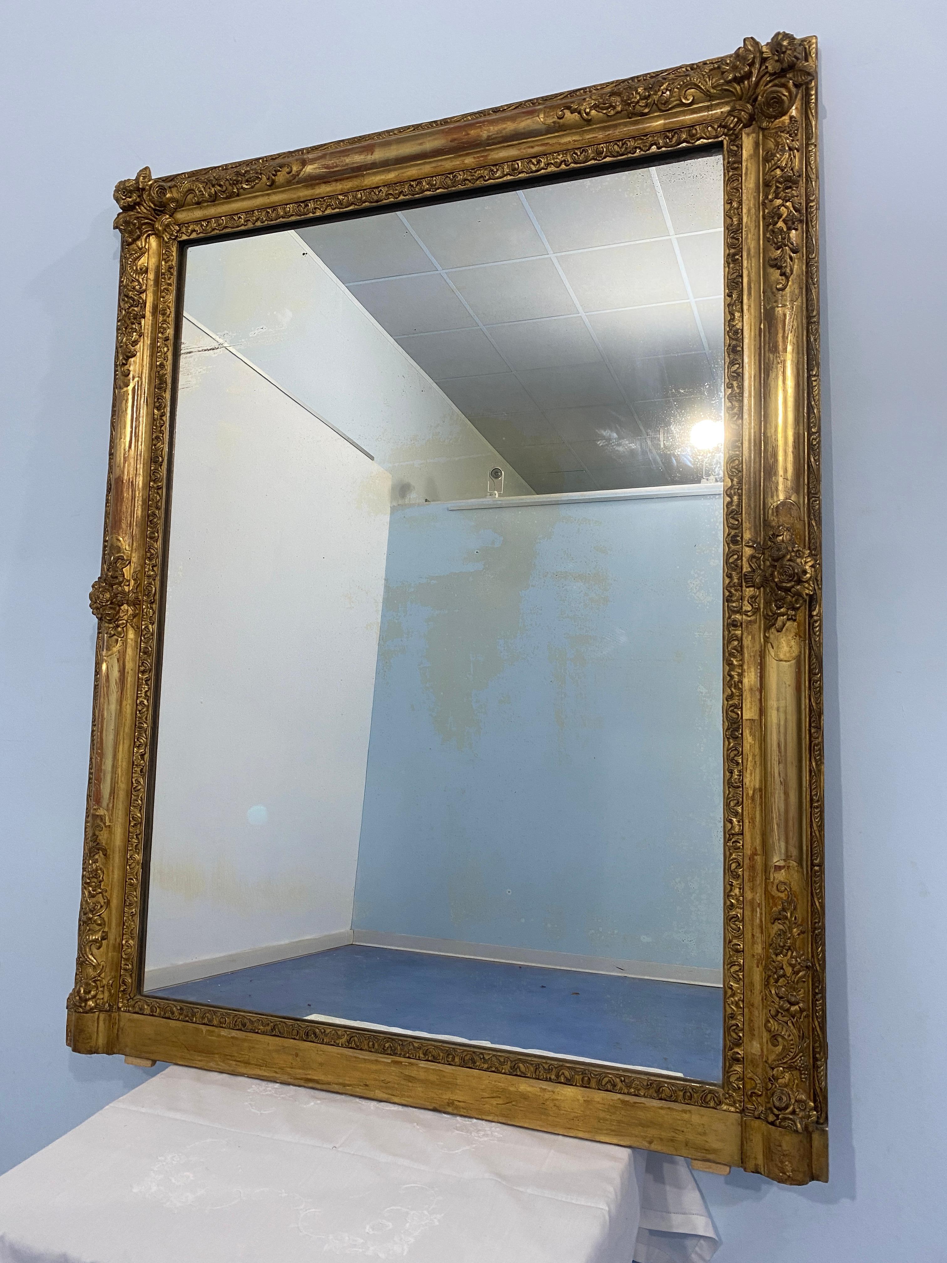 Raffinata specchiera francese epoca Napoleone Terzo, 1870, dorata a foglia d'oro. La cornice è ornata da splendidi motivi floreali a rilievo intagliati nel legno, ed è arricchita nella parte interna e nella parte esterna  da ulteriori motivi