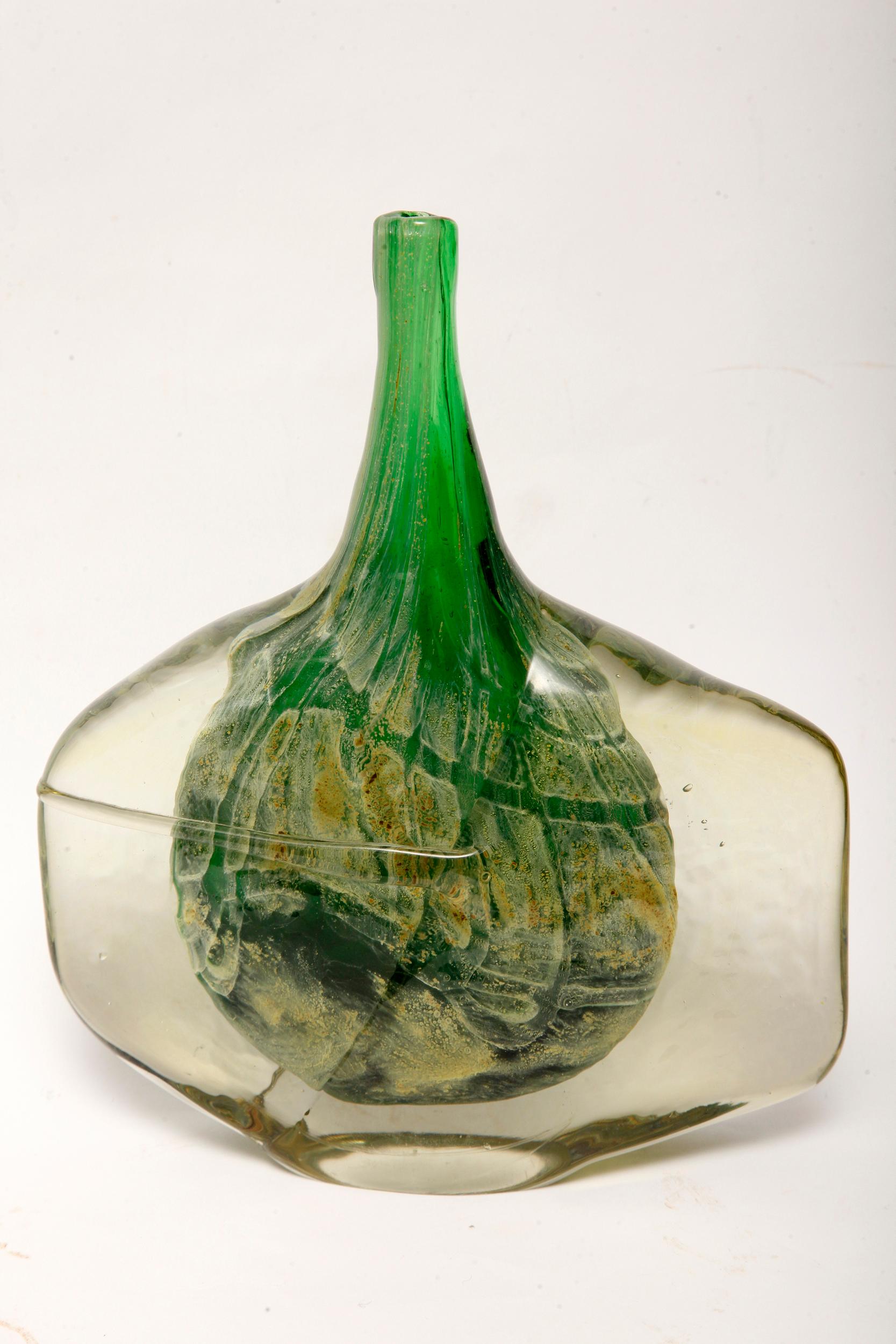 An absolutely stunning Mid-Century Modern green Axe Head vase by Michael Harris of Mdina Glass. Also referred to as a “Fish Head” and Lollipop vase.
The green glass is cased with a layer of clear, worked after being pulled from the fire and folded