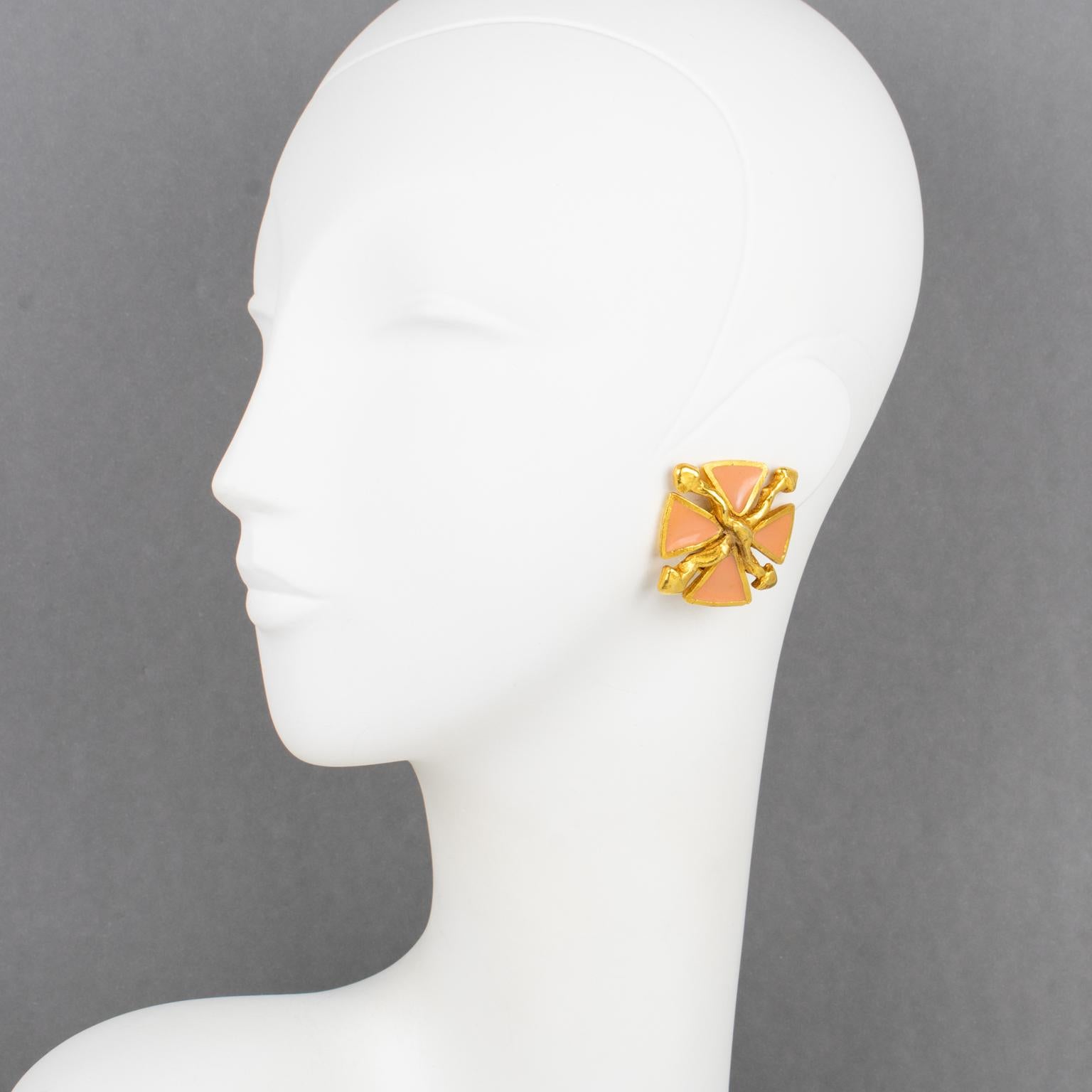 Antigona Paris designed those lovely clip-on earrings in the 1980s. The pieces boast a stylized Maltese cross design with gilt metal framing embellished with pink salmon enamel. Antigona Paris' hallmark is on the underside.
The earrings are in good