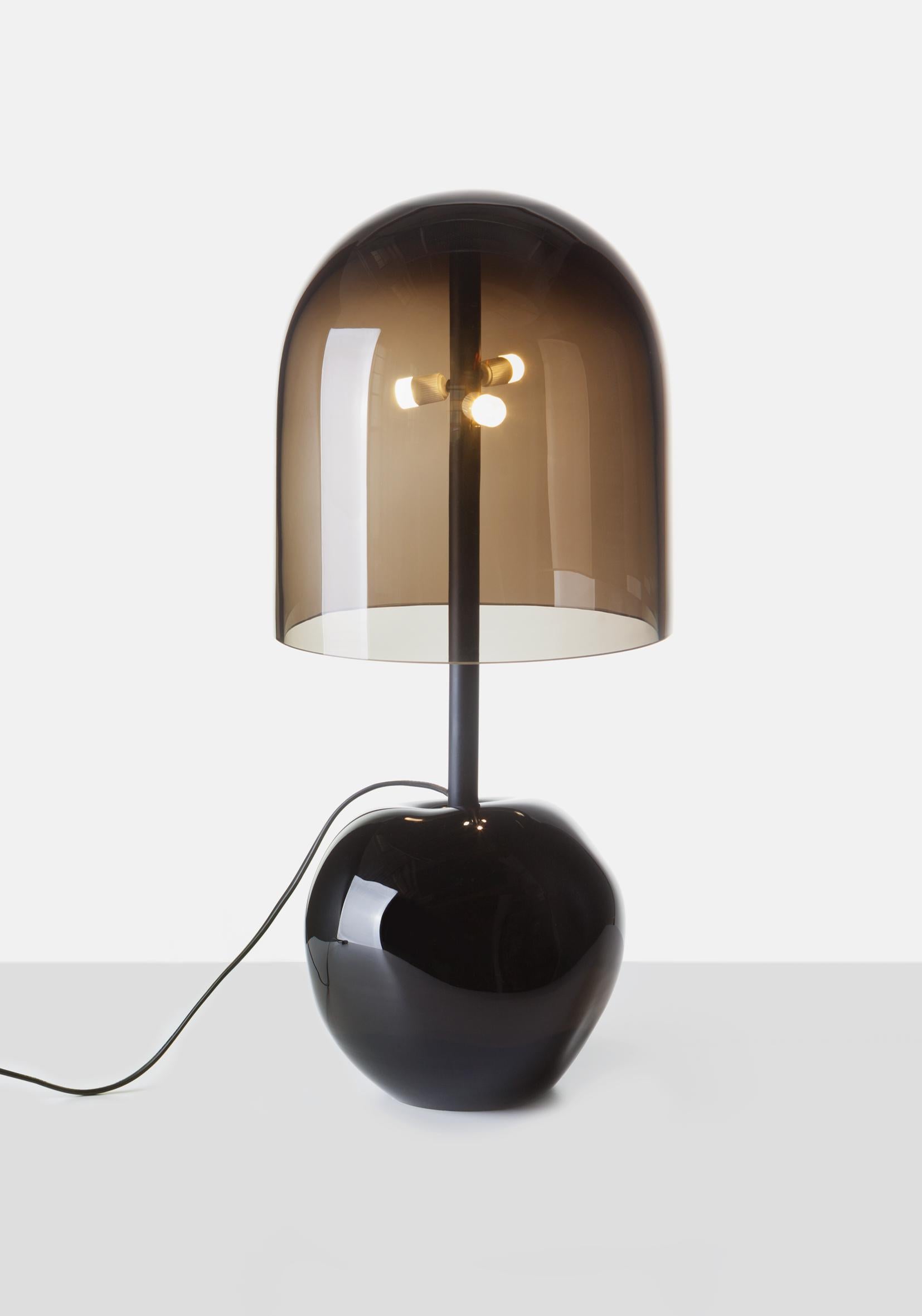 Antimatter floor lamp by Dechem Studio.
Dimensions: D 25 x H 55 cm.
Materials: glass, metal.

The massive, heavy and irregular black volume of the base contrasts with the light and precise glass dome of the shade. Black and smoke grey glass