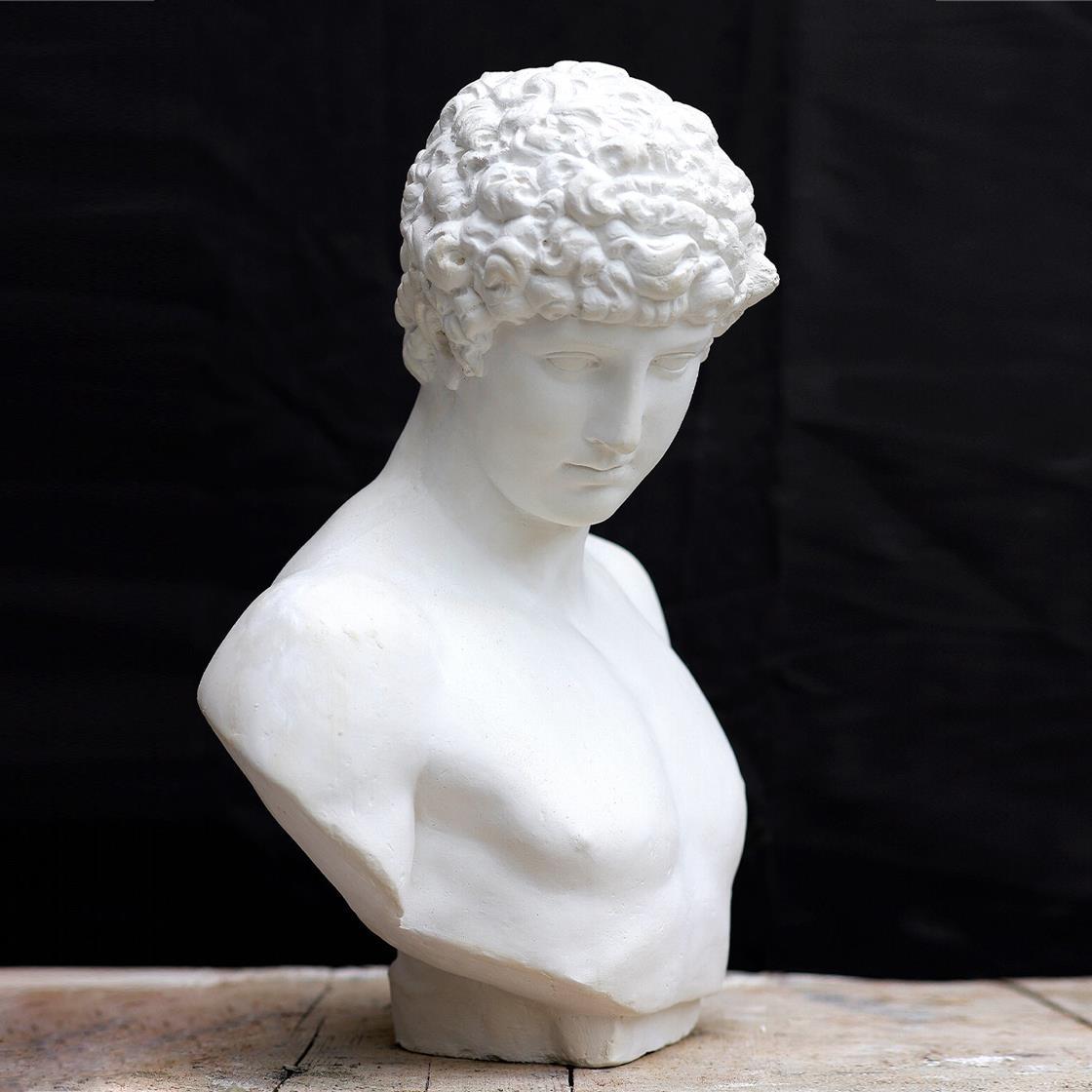 This plaster sculpture depicts the Greek Antinous, a favorite of Emperor Hadrian, who deified him after the youth's untimely, mysterious death. This work is made entirely by hand by craftsman at the Romanelli Gallery in Florence. It is based off an