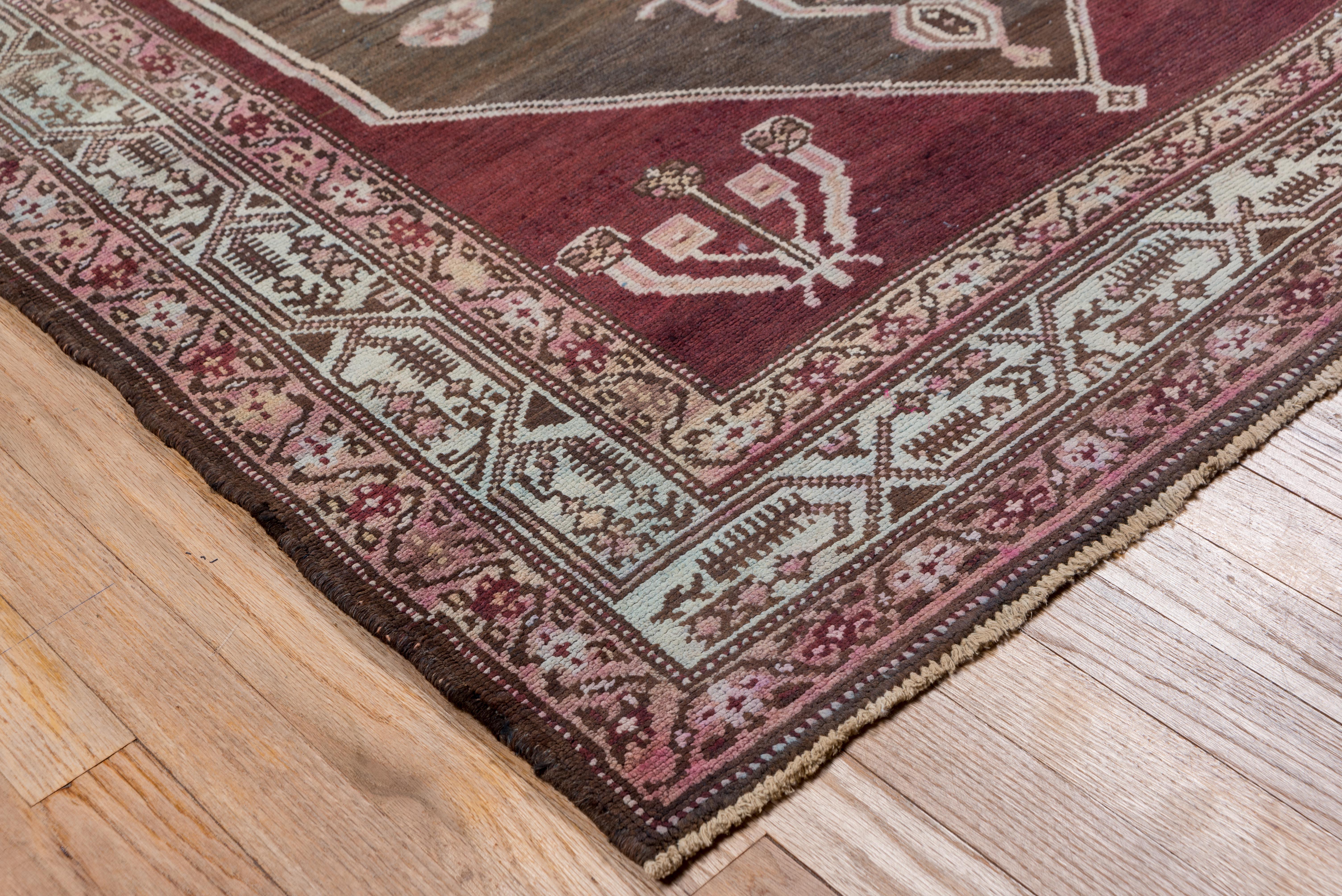 Dieser Medaillonteppich mit Stammesmotiv zeigt ein sanftes, verblasstes und doch tiefes, sattes Rot auf seinem Feld - mit akzentuierten Farben in den Bereichen Braun, Rostblau und Elfenbein, um nur einige zu nennen. 