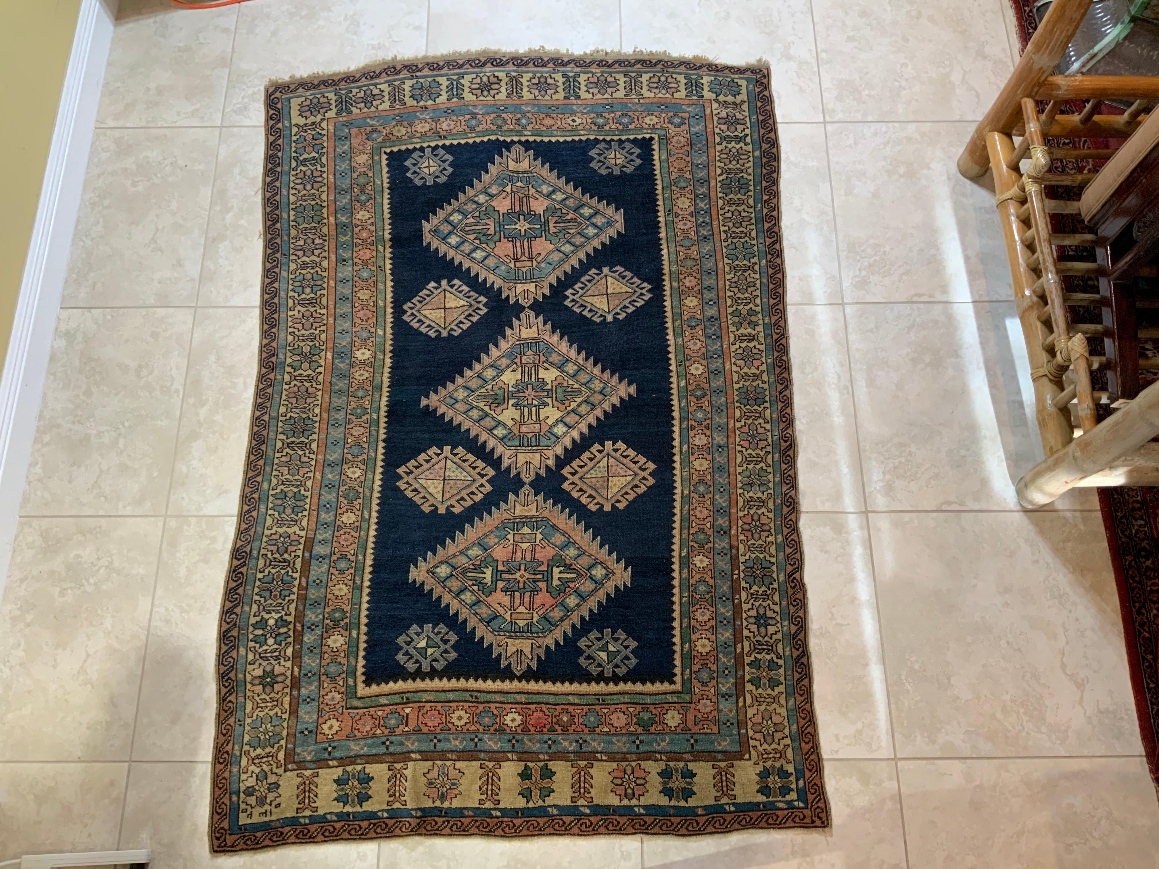 Elegant tribal Caucasian Kazak rug made of wool with beautifully executed geometric motifs of three large medallions and eight small one .deep blue center background, surrounded by eight intricate Borders. The rug is tightly handwoven, the rug is
