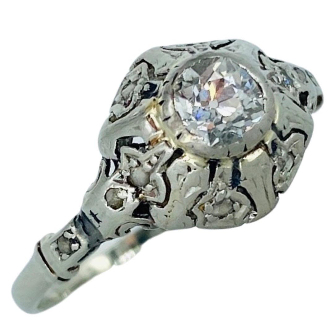 Antiker 0,56 Gesamtkarat Gewicht Diamant Verlobungsring 18k Weißgold
Der Ring hat einen zentralen Diamanten im europäischen Schliff mit einem Gewicht von ca. 0,45 Karat in einer Lünettenfassung, umgeben von 9 runden Diamanten im Einzelschliff mit