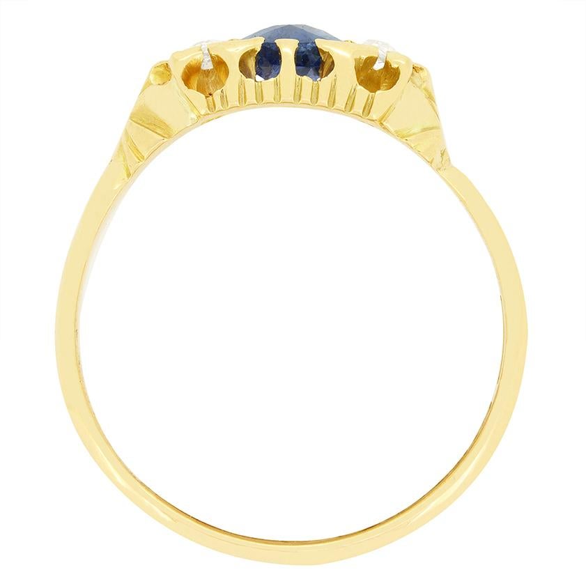A stunning blue sapphire is flanked by old cut diamonds in this wonderful antique ring hallmarked 1902. The central sapphire is an oval cut stone weighing 0.60 carat. The accompanying diamonds weigh 0.05 carat each, for a total of 0.20 carat, with