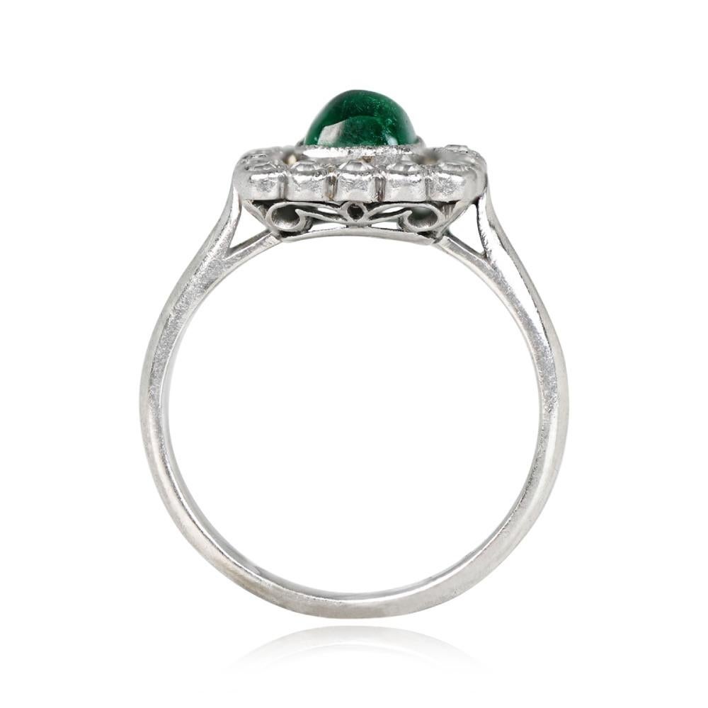 An authentic antique ring showcases a 0.75-carat natural green sugarloaf cut emerald. The center stone is encircled by a halo of old European cut diamonds, all set in platinum. This Edwardian-era piece hails from around 1900.

Ring Size: 6.5 US,
