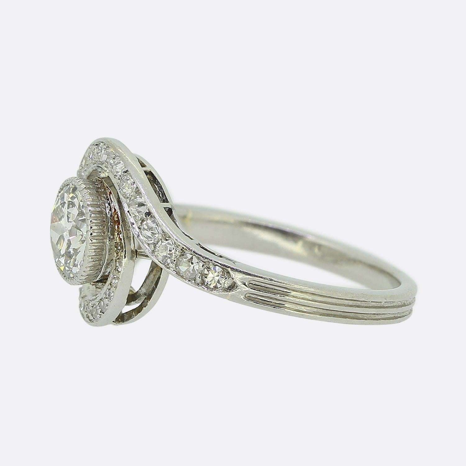 Here we have a fabulous diamond swirl ring dating back to the Edwardian period. This antique piece showcases a single round faceted old European cut diamond at the centre of the face in a fine milgrain setting. This principle stone sits slightly