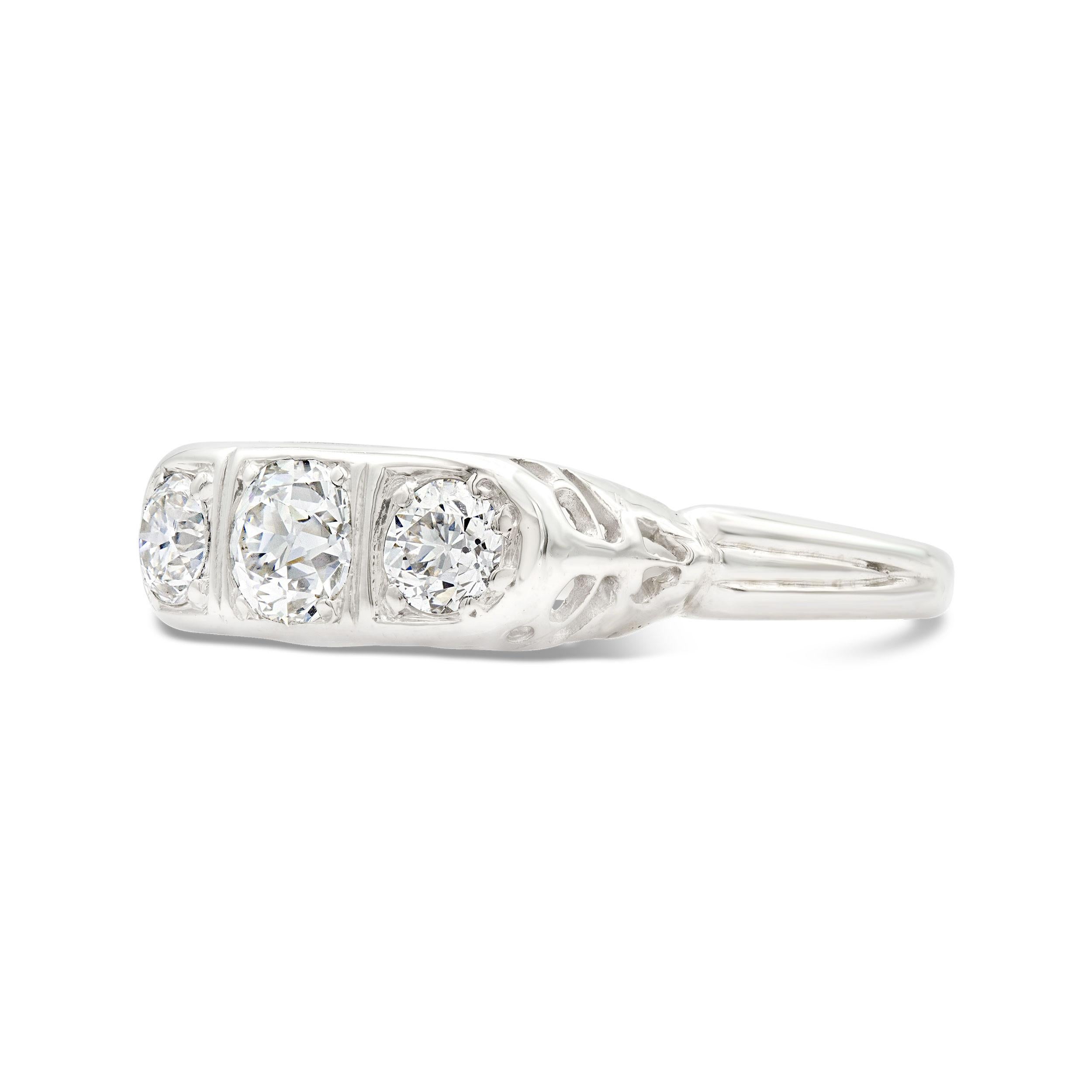 A beyond charming diamond trilogy ring features three twinkling old European cut diamonds weighing 0.85 carats total. The gallery of the ring features unique filigree work, hand crafted in platinum. The diamonds offer up finger-spanning sparkle that