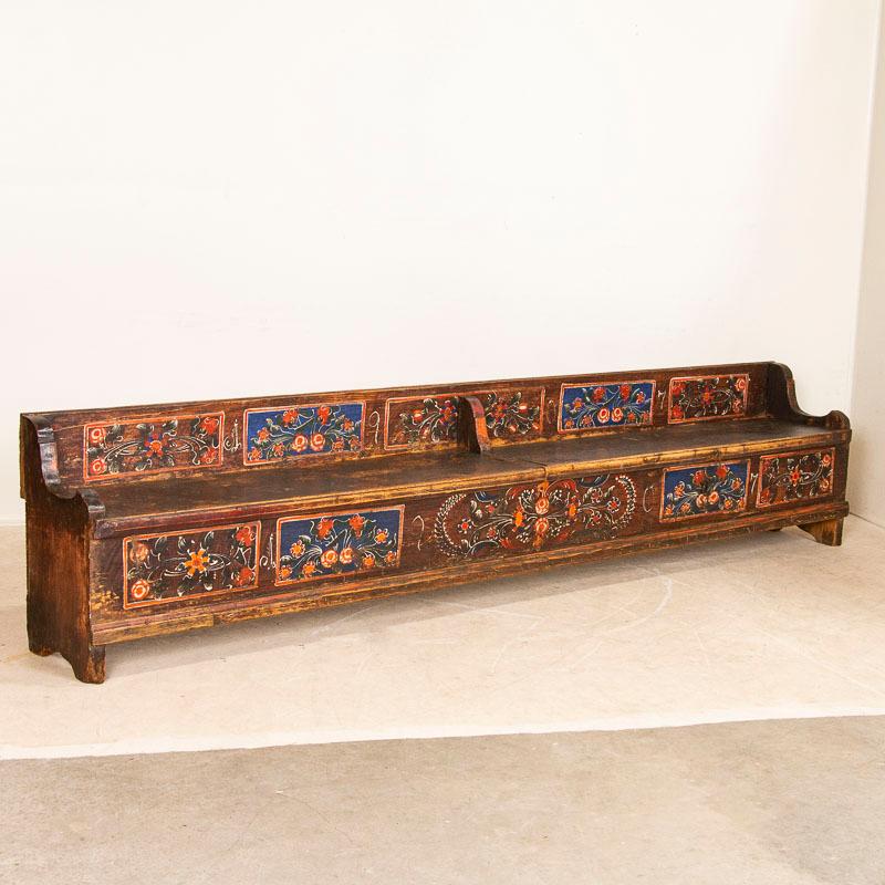 This 10' long antique pine bench from Romania still maintains the original folk art paint from 1907, when it was created. The traditional folk art of the late 1800's into 1900's included floral motifs painted in panels, often done in blue or red