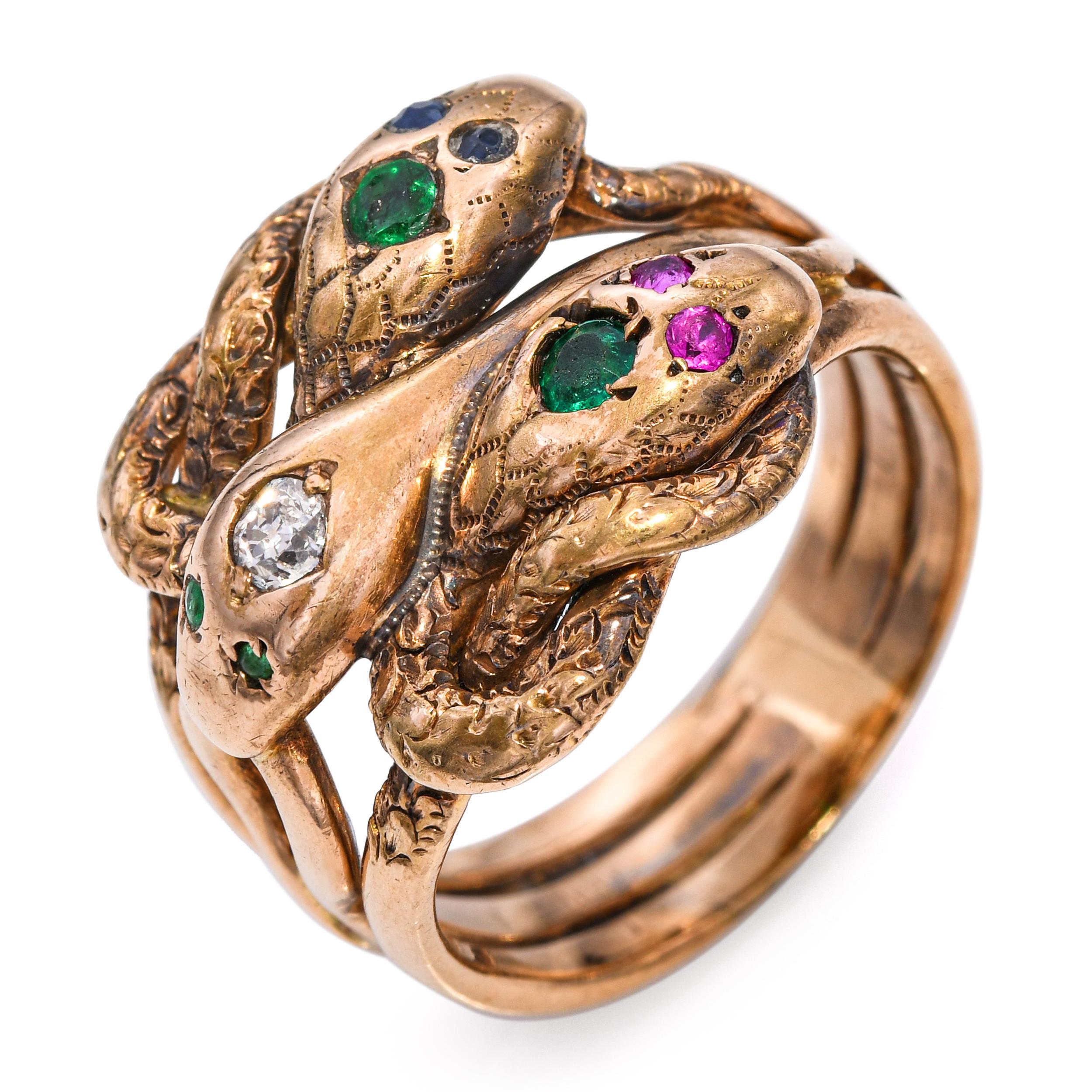 Dieser antike Ring ist ein eindrucksvolles Beispiel für die viktorianische Symbolik. Er zeigt drei ineinander verschlungene Schlangen, die jeweils mit ihren eigenen Edelsteinaugen - Rubin, Saphir, Smaragd - gekrönt sind und von denen eine mit einem