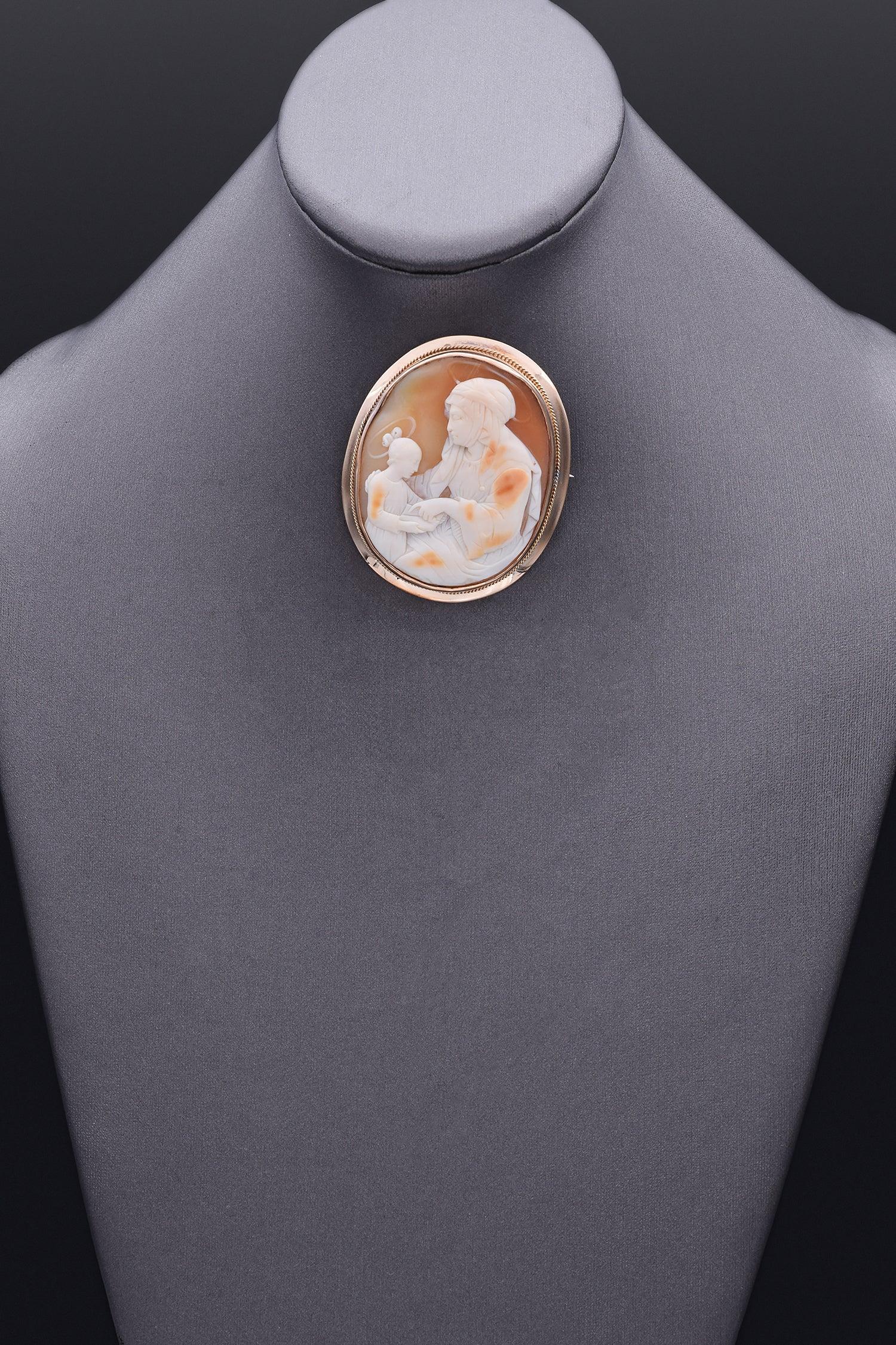 Elegant and timeless, this Education of the Virgin Mary by Saint Anne cameo brooch pendant features a finely carved scene of Saint Anne teaching the young Virgin Mary. Set in a radiant yellow gold frame with delicate rope detailing, this piece