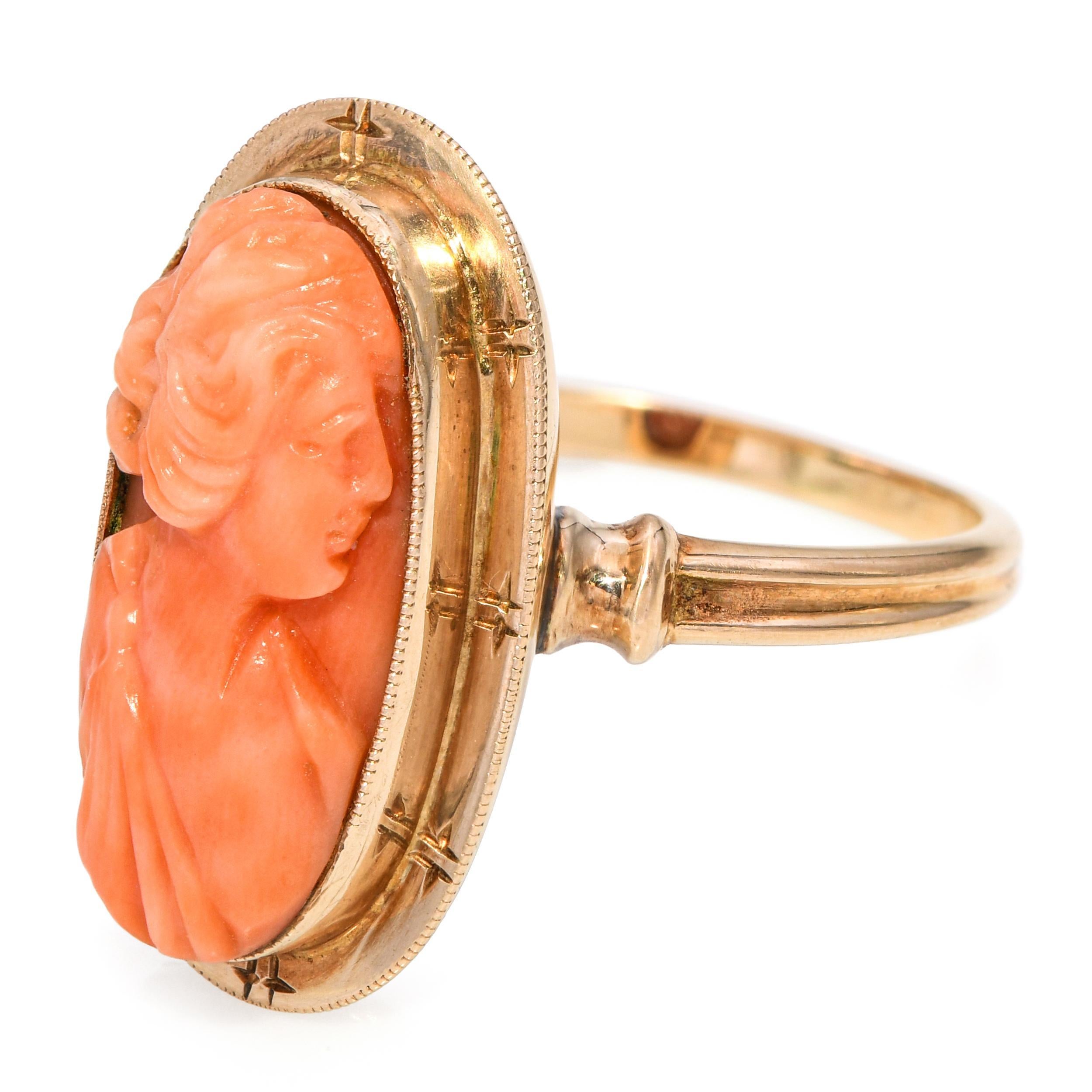 Bague ancienne en or jaune 10k avec camée en corail, présentant un camée en corail finement sculpté dans des tons naturels chauds, serti dans une monture classique en or jaune. Les détails délicats du camée reflètent l'art de son époque, tandis que