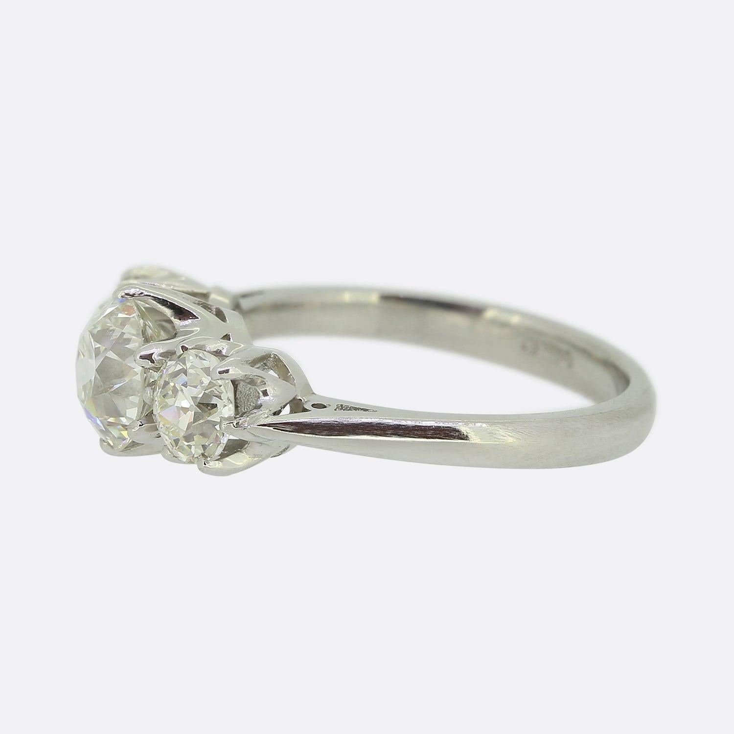 Aquí tenemos un maravilloso anillo de diamantes de tres piedras. Elaborada en platino, esta pieza exhibe un trío de asombrosos diamantes redondos facetados de talla antigua, el mayor de los cuales se alza orgulloso en el centro con un peso de 1,10