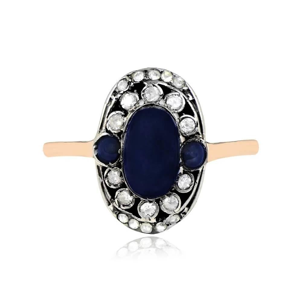 An antique ring featuring a 1.15-carat cabochon sapphire center, elegantly accented by two additional sapphires on each side, weighing approximately 0.20 carats each. The center sapphire is embraced by a halo of both old European cut and old