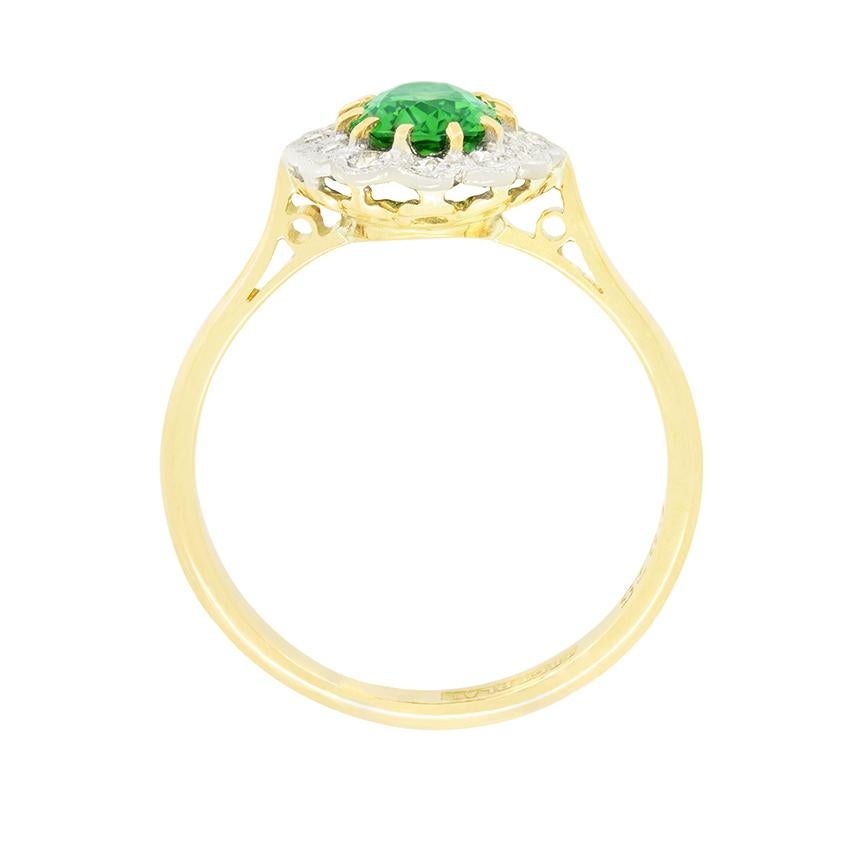 A gorgeous green tourmaline sits central in this 1930s cluster ring. Weighing 1.20 carat the oval cut tourmaline is claw set into platinum and surrounded by a halo of eight cut diamonds. Totalling 0.12 carat the diamonds match in quality at H in