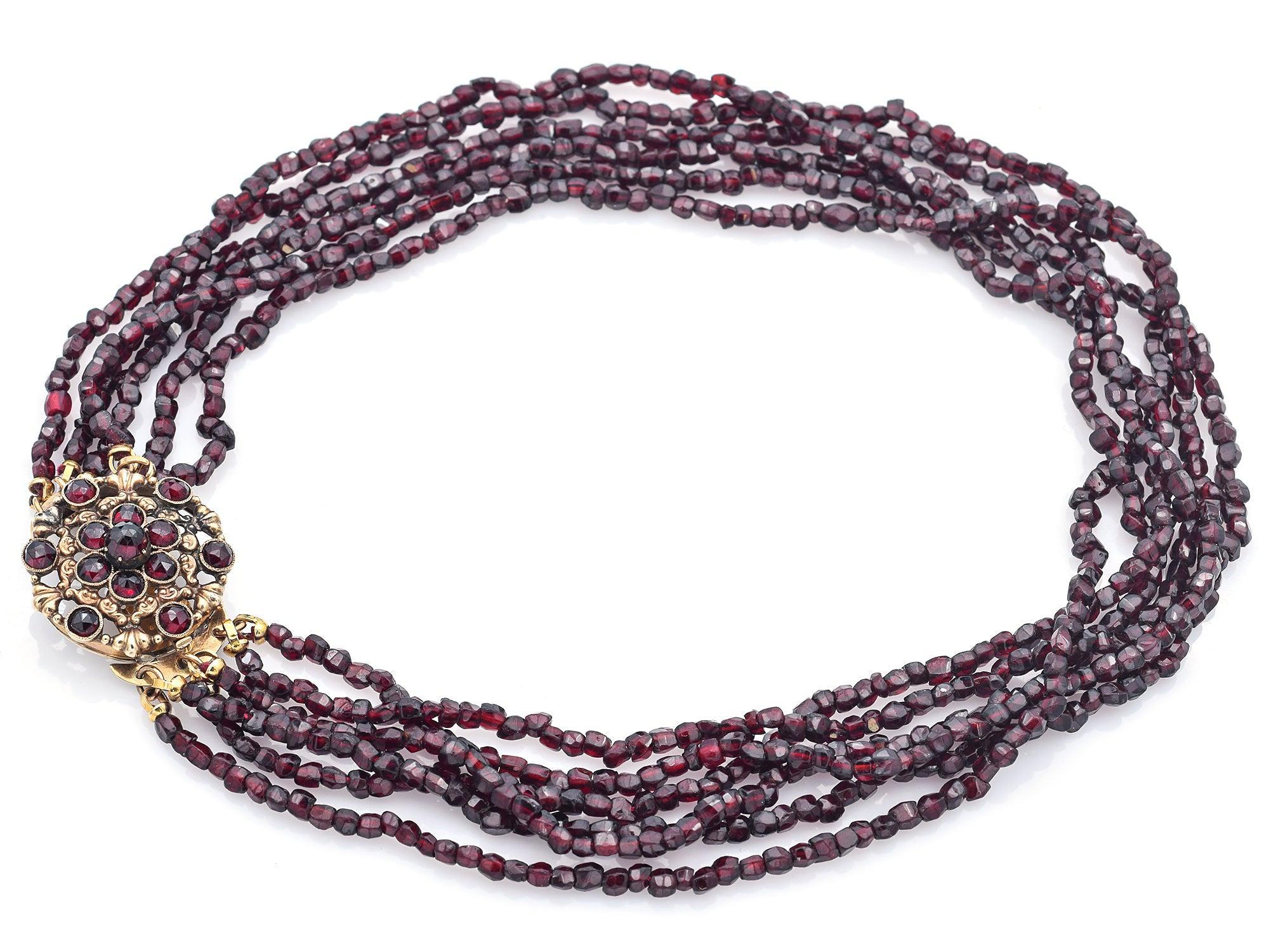 Antique multi-strand garnet necklace featuring rich, garnet beads and a decorative 12k yellow gold floral clasp set with garnets. The elegant flower motif adds a timeless touch, making this piece both functional and beautifully ornamental.

Weight: