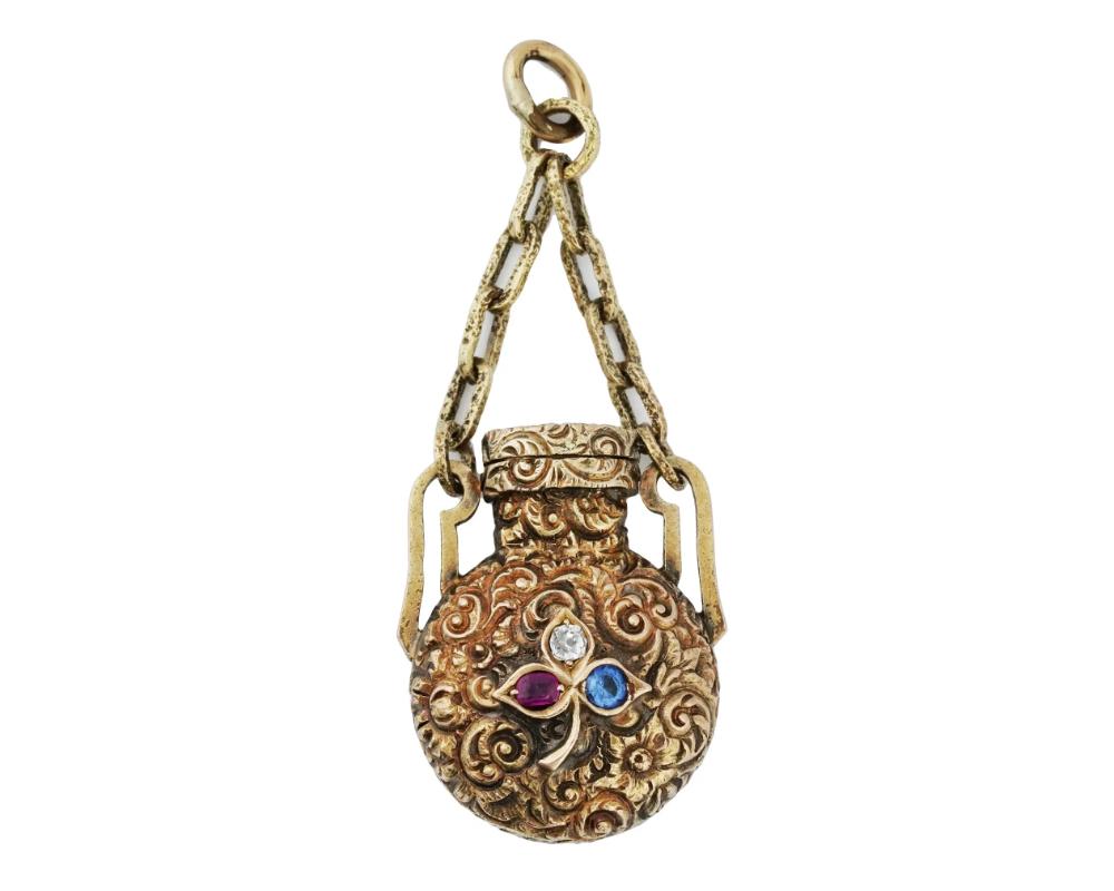An antique Victorian 14K gold perfume bottle, circa the mid 19th century. The piece is modeled as a miniature vessel of a round shape, adorned with finely detailed hand carved floral patterns and set with a ruby, a sapphire and a diamond to the