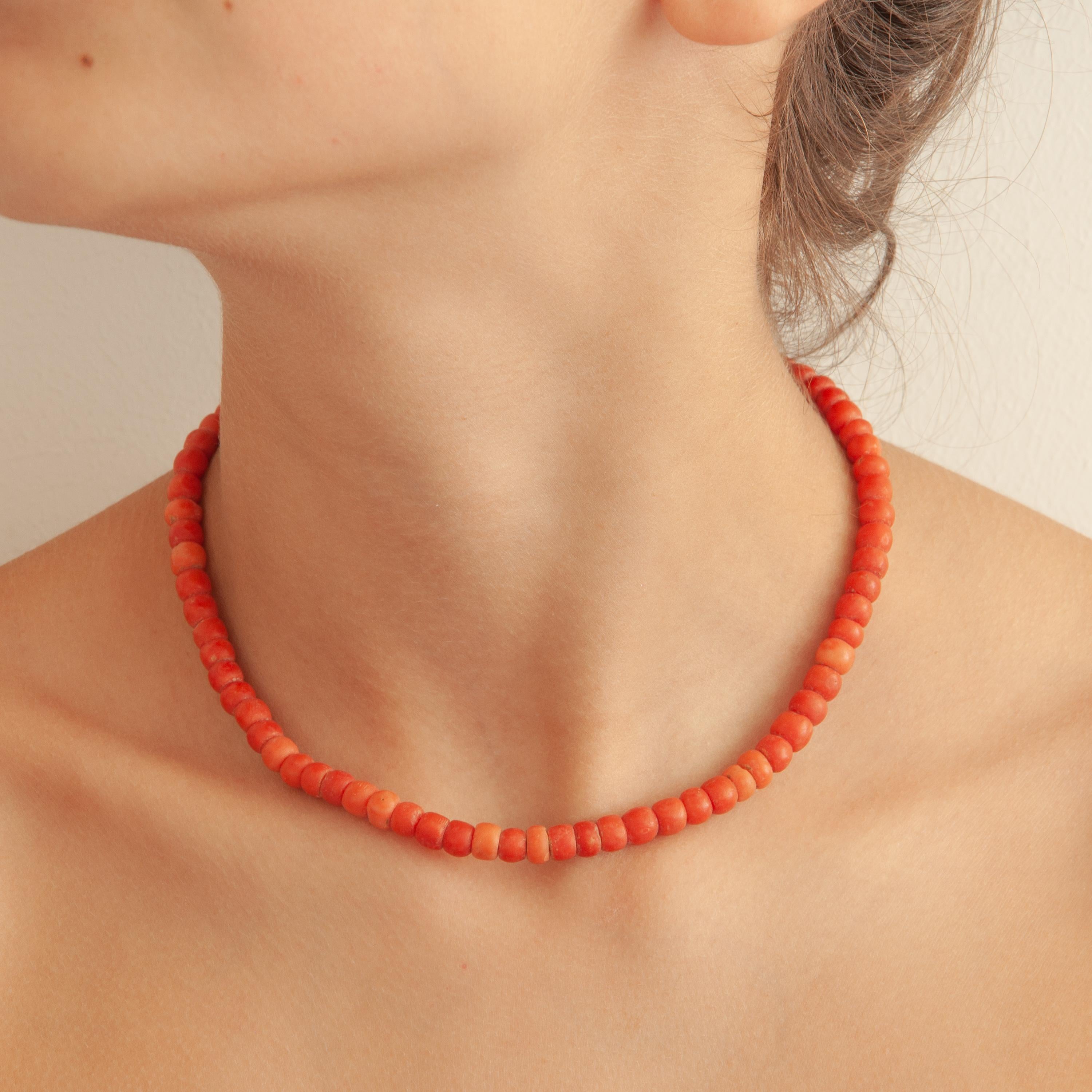 A gorgeous mid-century natural coral necklace set with a 14 karat gold clasp. The coral beads on this necklace are barrel-shaped and some differ slightly in color. The coral stones have a diameter of approximately 6 millimeters. The oval-shaped 14