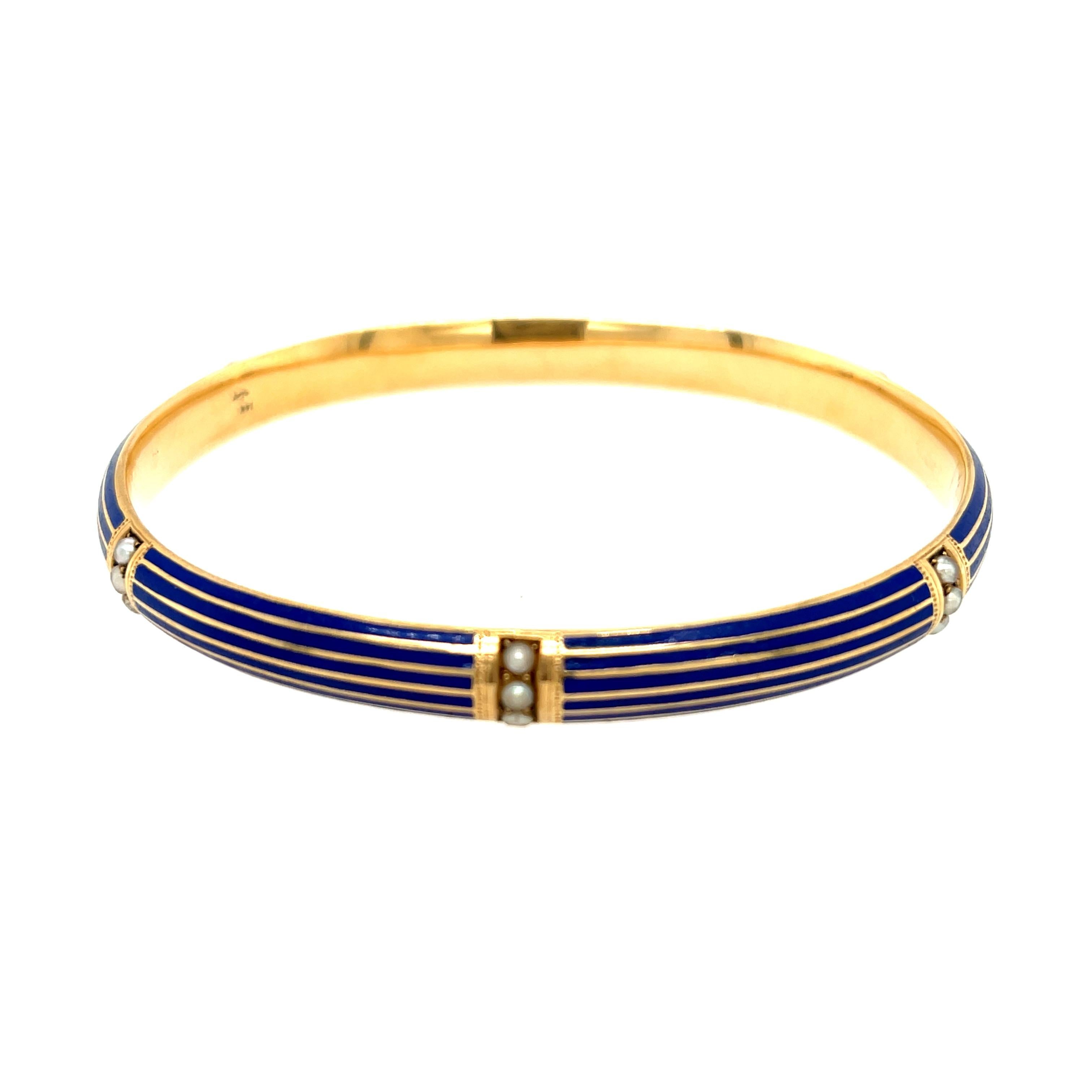 A turn of the century 14k gold blue enamel and seed pearl bangle bracelet by Riker Brothers, circa 1900. This stylish bangle was made by a prominent Newark, New Jersey gold manufacturer. They are well known for making such slip on bangles. This
