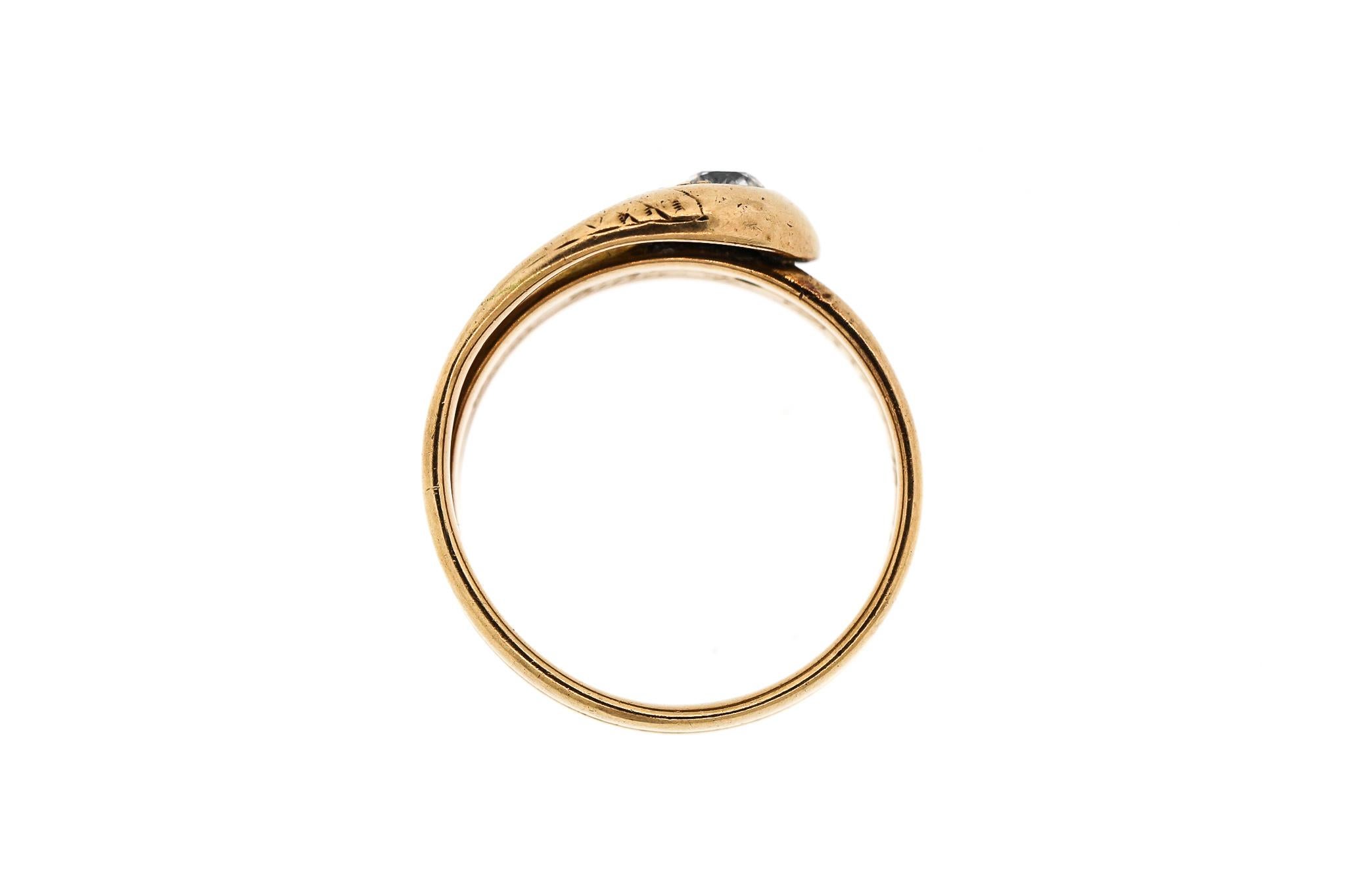 A coiled 14k yellow gold coiled snake ring set with an Old European cut diamond and two small single cut diamonds dating to about 1900. The ring bears an inscription 