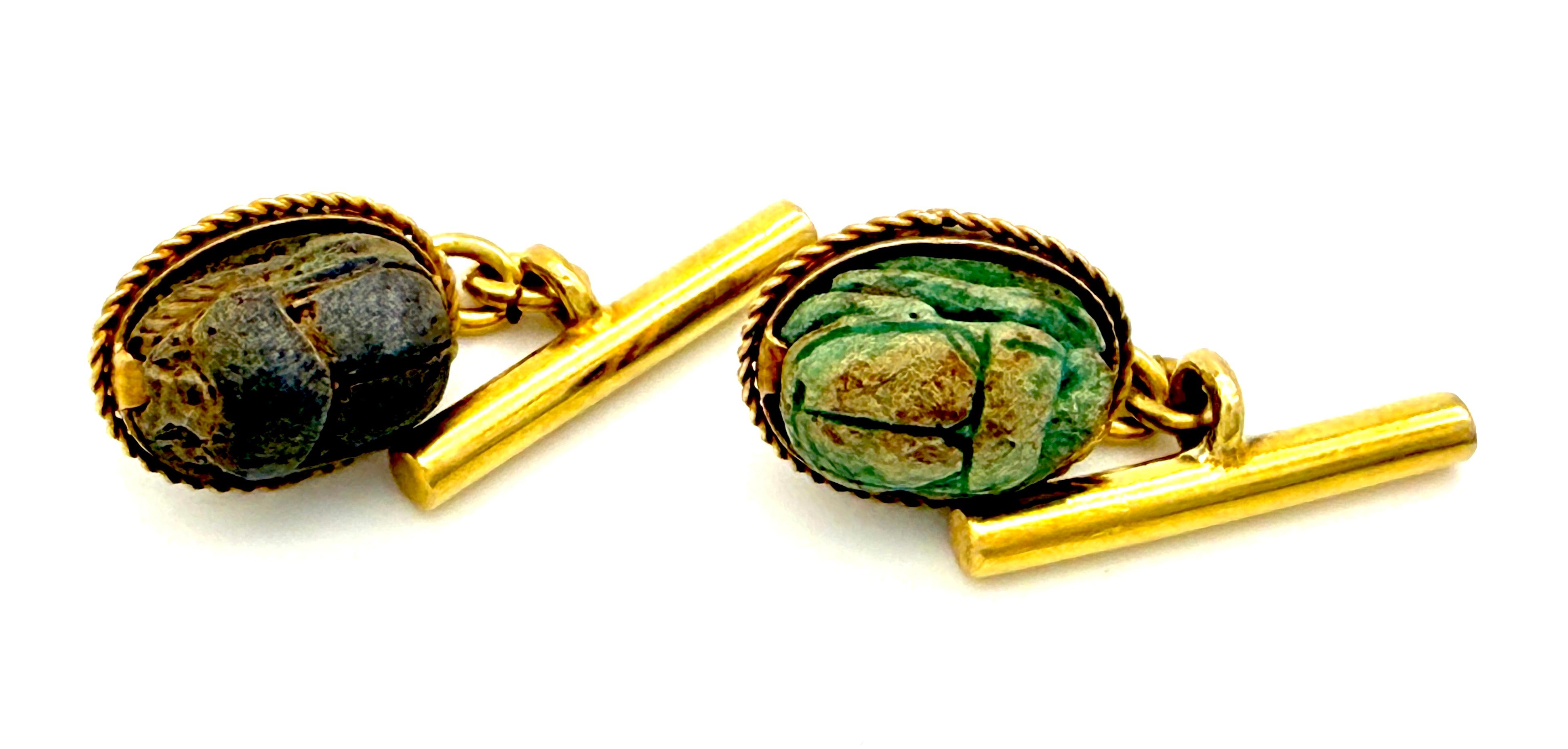 This exquisite pair of cufflinks was created in the last 3rd of the 19th century in the Egyptian Revival taste. The cufflinks are made out of 14K gold. The faience scarabs are mounted in gold settings decorated with twisted gold wire all around. The