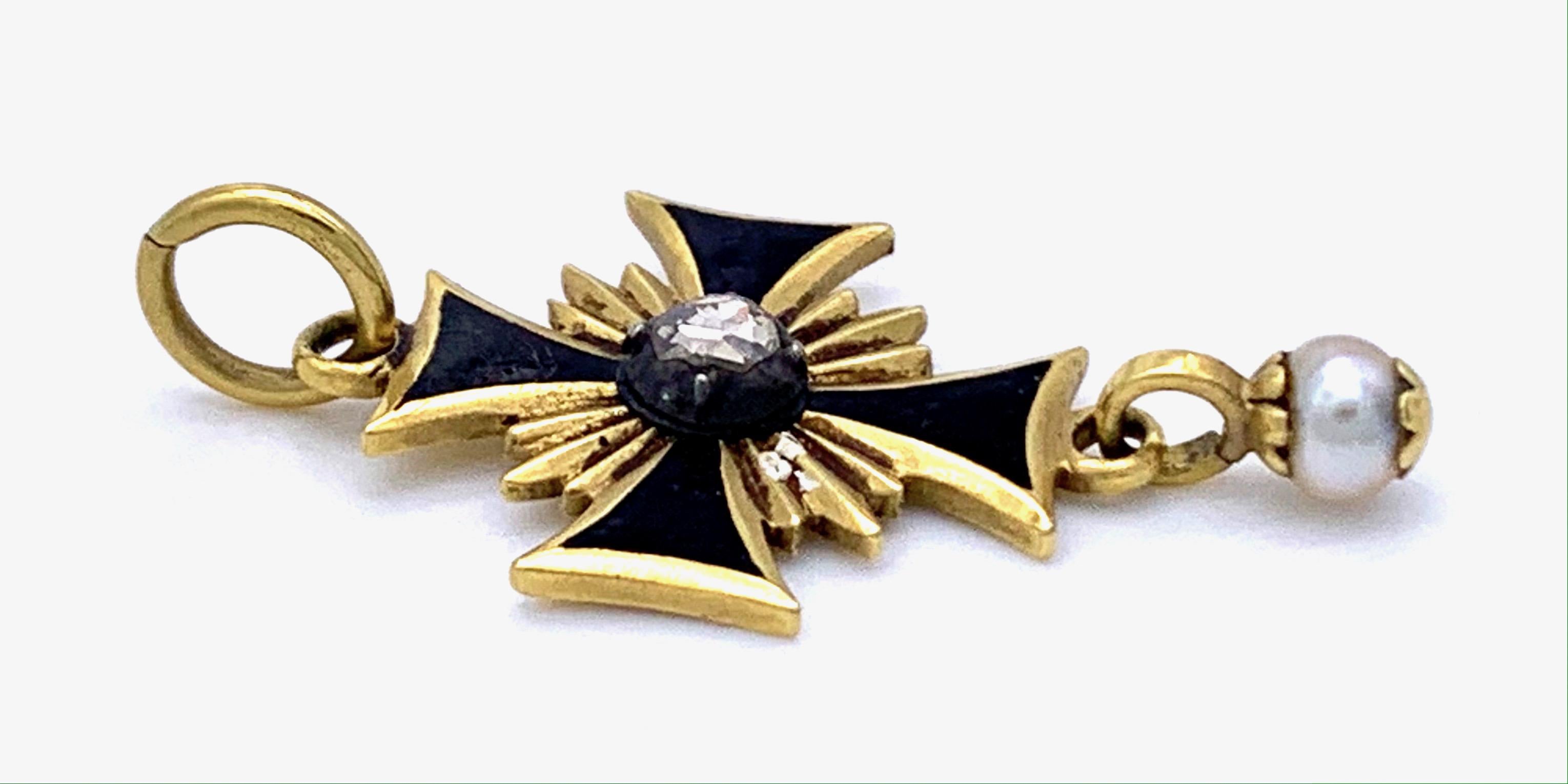 This small 14 karat gold cross is decorated with a silver mounted diamond and has a a natural oriental pearl suspended from it. It is highlighted with black enamel.