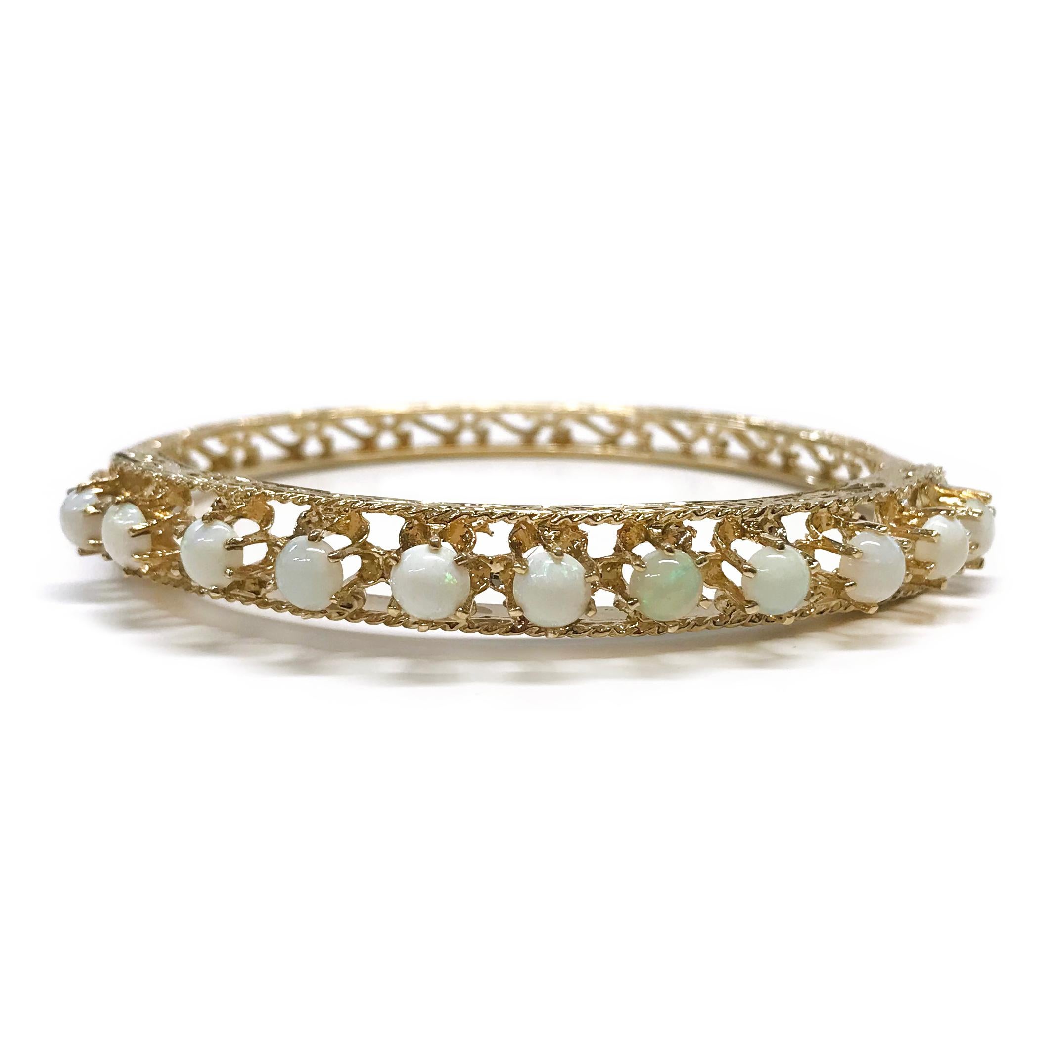 Antique 14 Karat Opal Bangle Bracelet. Eleven prong-set Opals adorn this lovely hinged bangle bracelet. The white Opals have a play of color in green and pinkish-red. There is substantial detail in this piece, making it extra special with cutout