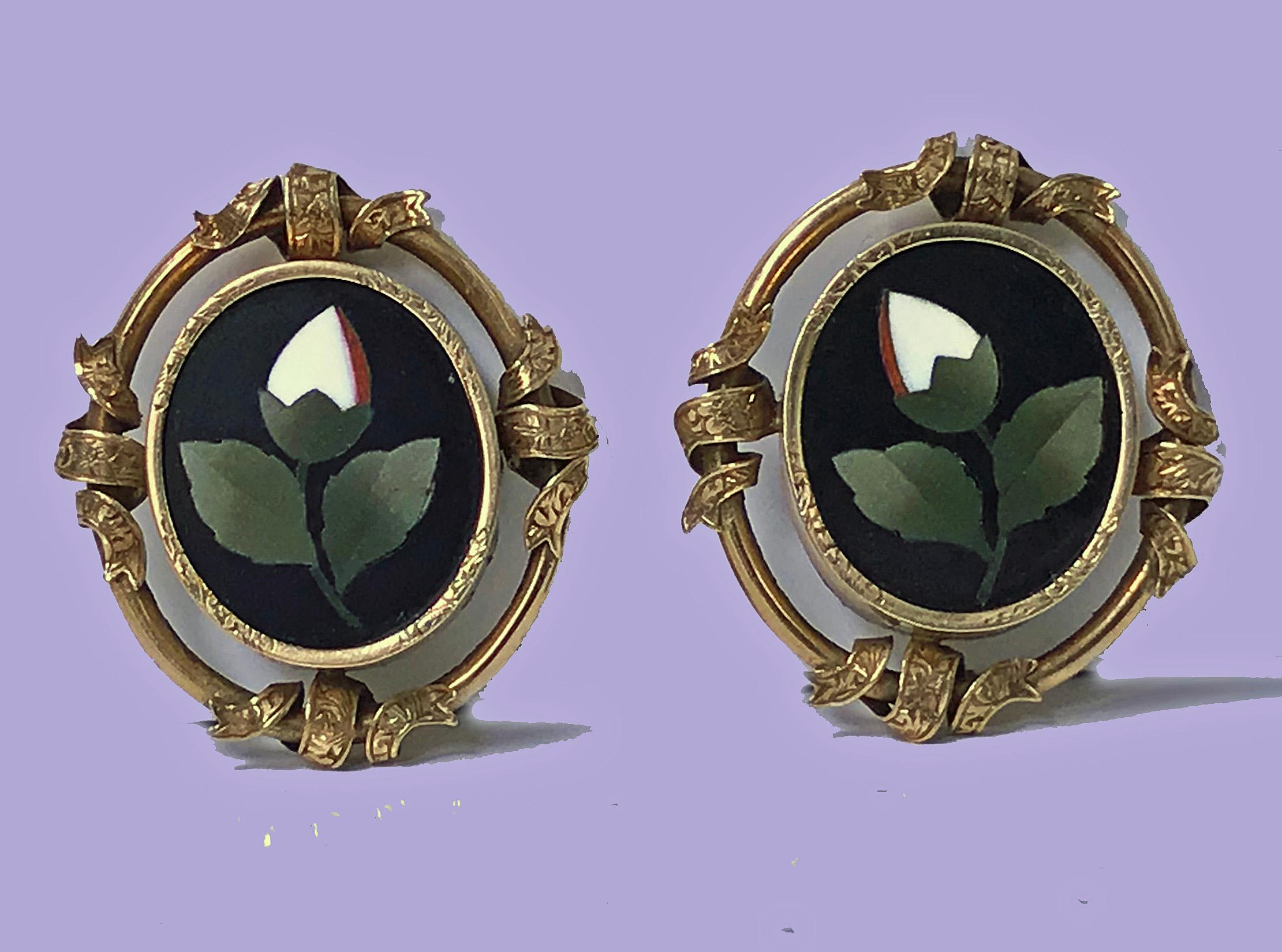 Pair of Antique 14K Pietra Dura Earrings, C.1875. Each of oval form, bezel set oval pietra dura floral white, green orange inlay colours, the surround gold mount interspaced ribbon design, clip fitments. Gold acid tests 14K. Measures: 1.25 x 1.00