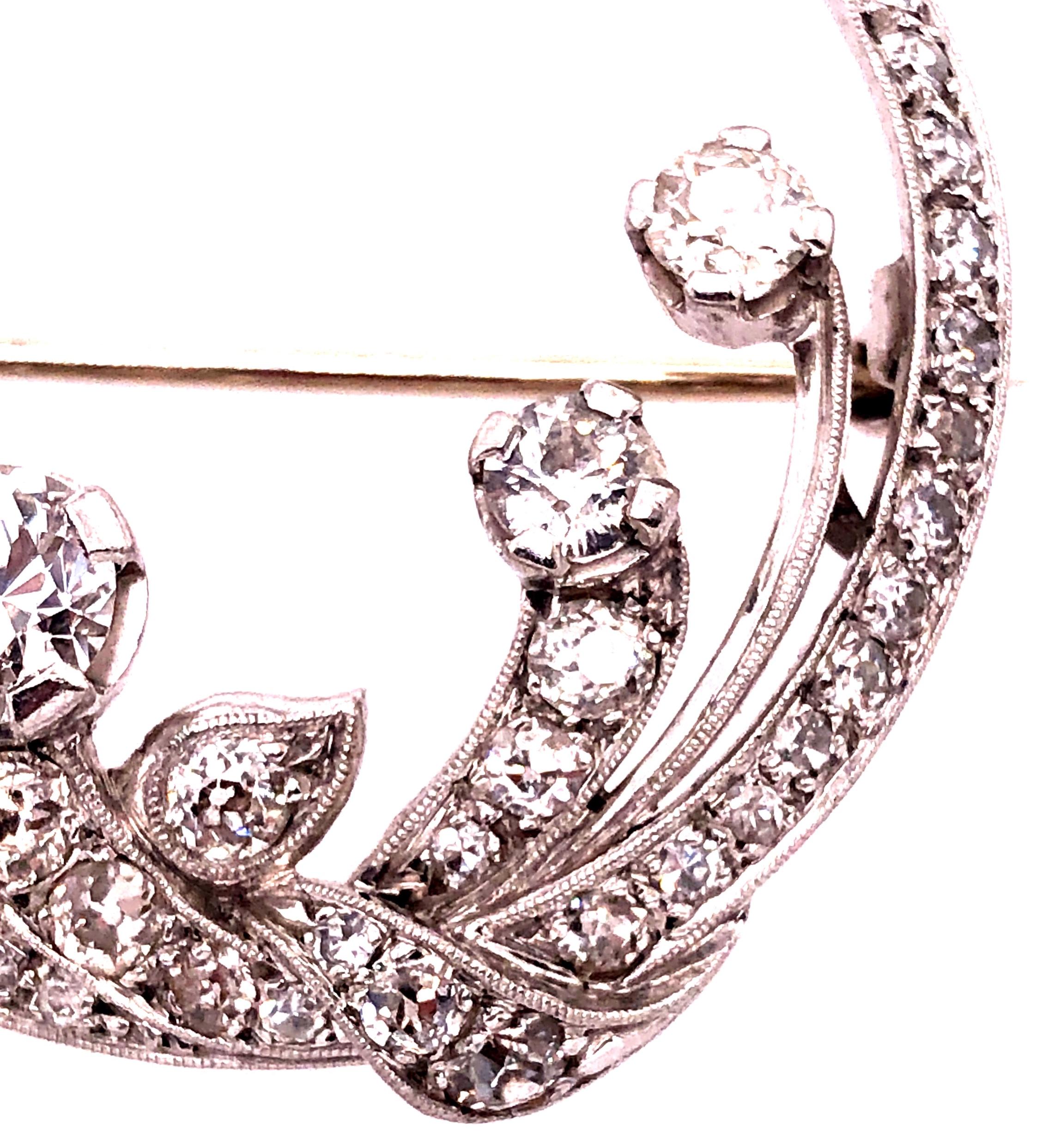 14 Karat White Gold Vintage Diamond Circle Pin / Brooch having a floral design set with a large .60 round diamond of excellent quality in the center flanked by three .20 round diamonds and eight graduating diamonds leading to a circular frame of 45
