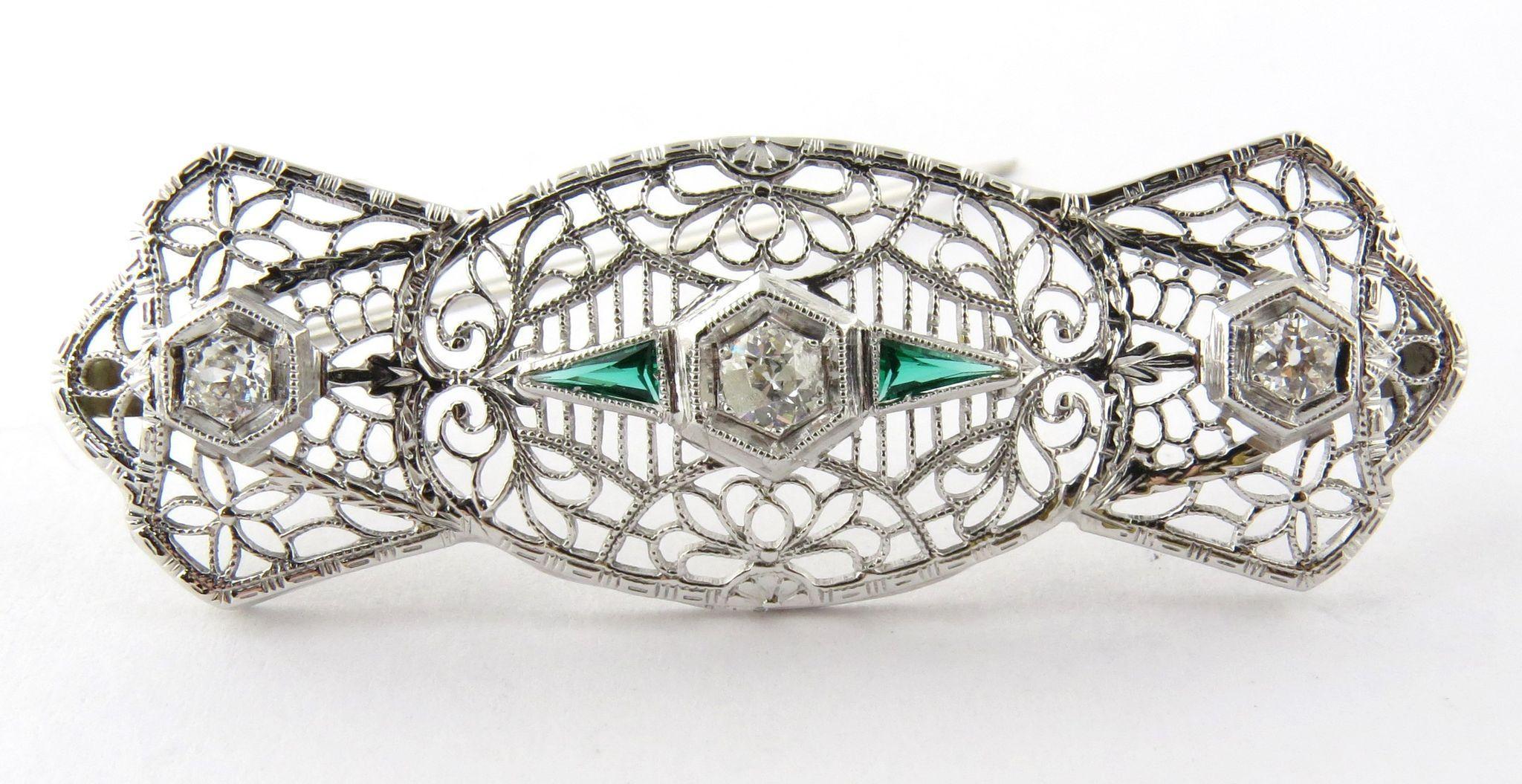 Antique 14K White Gold Art Deco Diamond and Emerald Filigree Brooch Pin. 

Lacy bow tie style brooch with 3 diamonds and 2 triangle emeralds. 

Measures: 47mm x 15mm (1 13/16