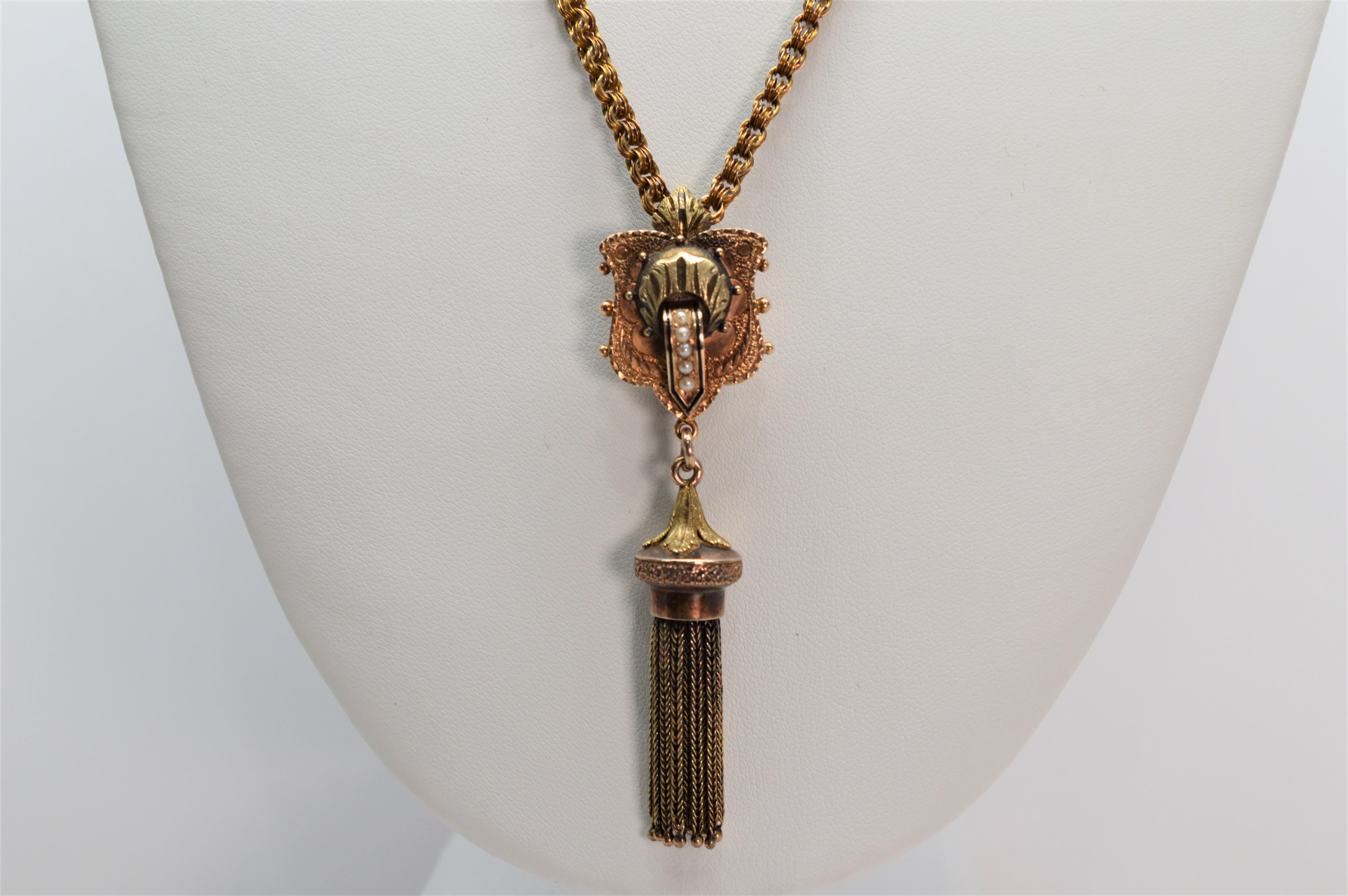 Antique and unique, this elegant pendant with dangling tassels presents an artisan quality and the design of opulence from an era gone by. This regal pendant adorned with tiny pearls, measures
 3 inches in length from top of pendant shield to bottom