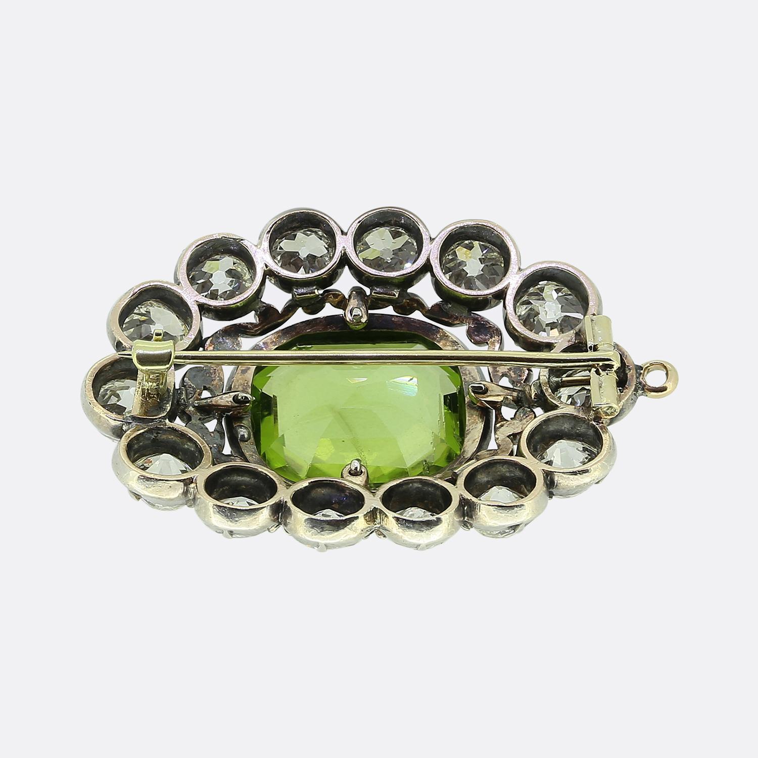 Nous avons ici une broche antique exquise avec au centre un impressionnant péridot de 15,00 carats taillé en émeraude. Cette pierre principale possède une teinte verte vibrante qui est accentuée par un cadre de diamants roses scintillants. Des