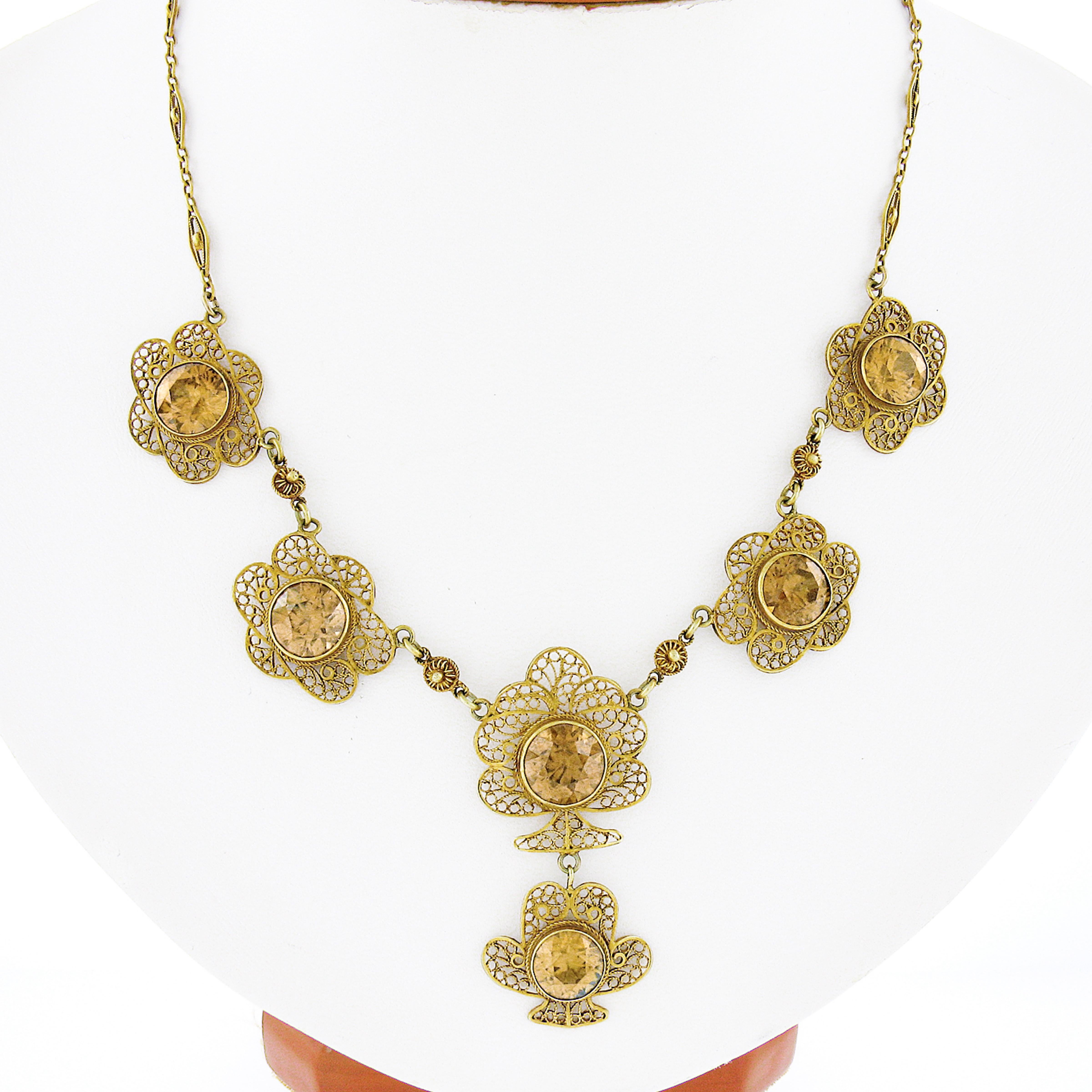 This magnificent and unique antique pendant necklace was crafted during the art nouveau period in solid 14k yellow gold. The center of the necklace features gorgeous open filigree work floral shaped links that are each bezel set with a fine quality
