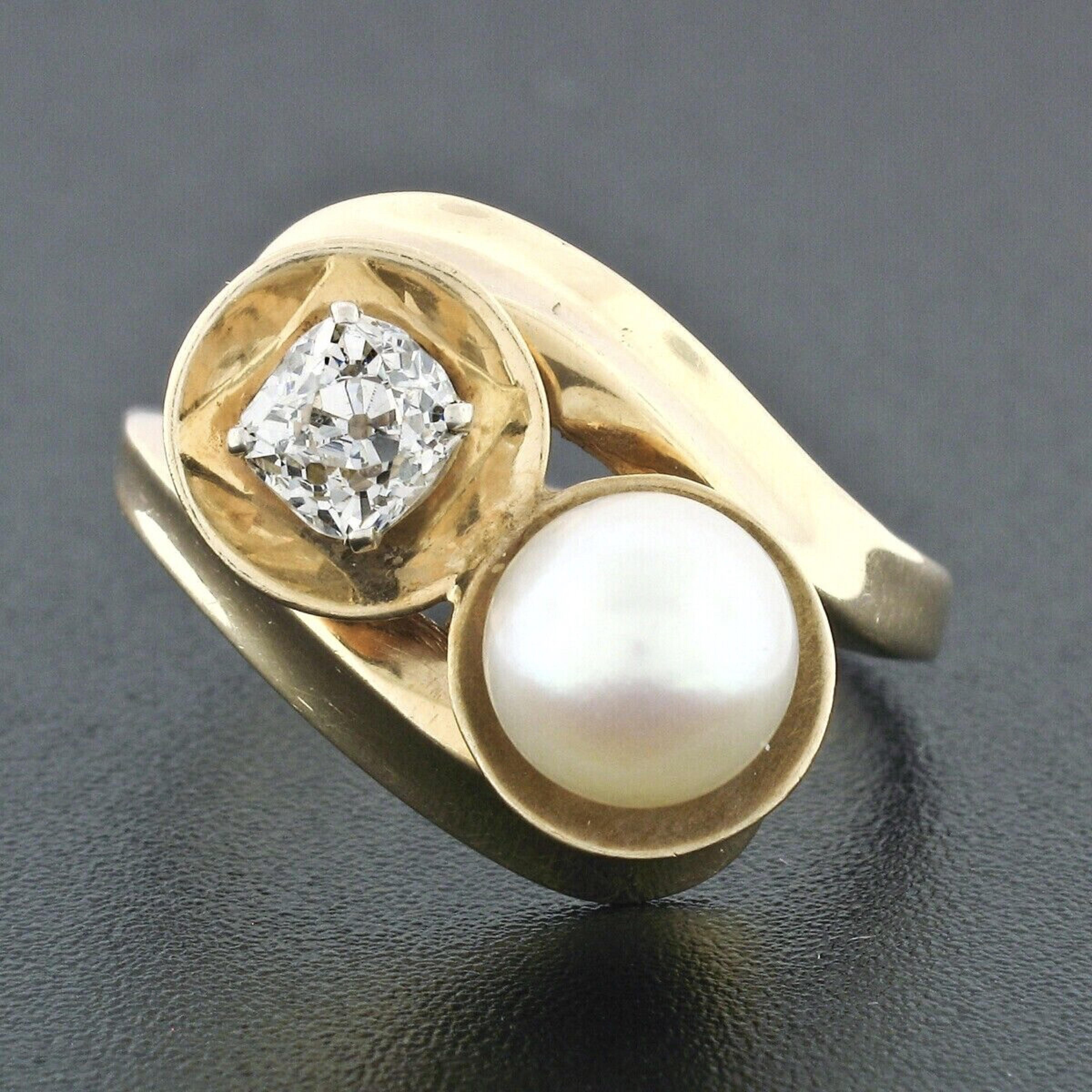 Here we have a handmade antique cocktail ring crafted in solid 14k yellow gold and features a fine quality pearl and an old cut diamond, both sitting on either side of the elegant bypass design. The beautiful pearl is round shaped with nice large