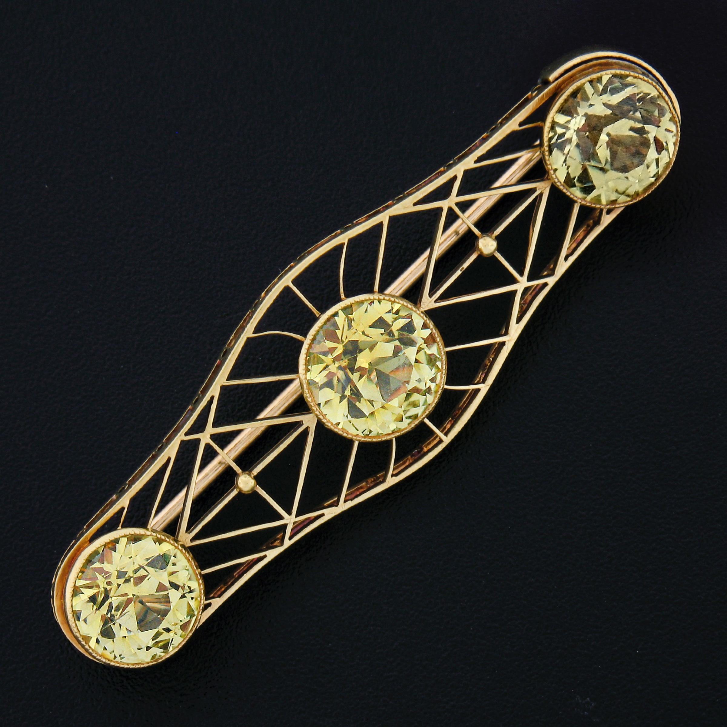 This breathtaking and well made antique brooch is crafted in solid 14k yellow gold and features a truly elegant mosaic open work design that is neatly milgrain bezel set with 3 gorgeous synthetic sapphire stones across their center. Two of these