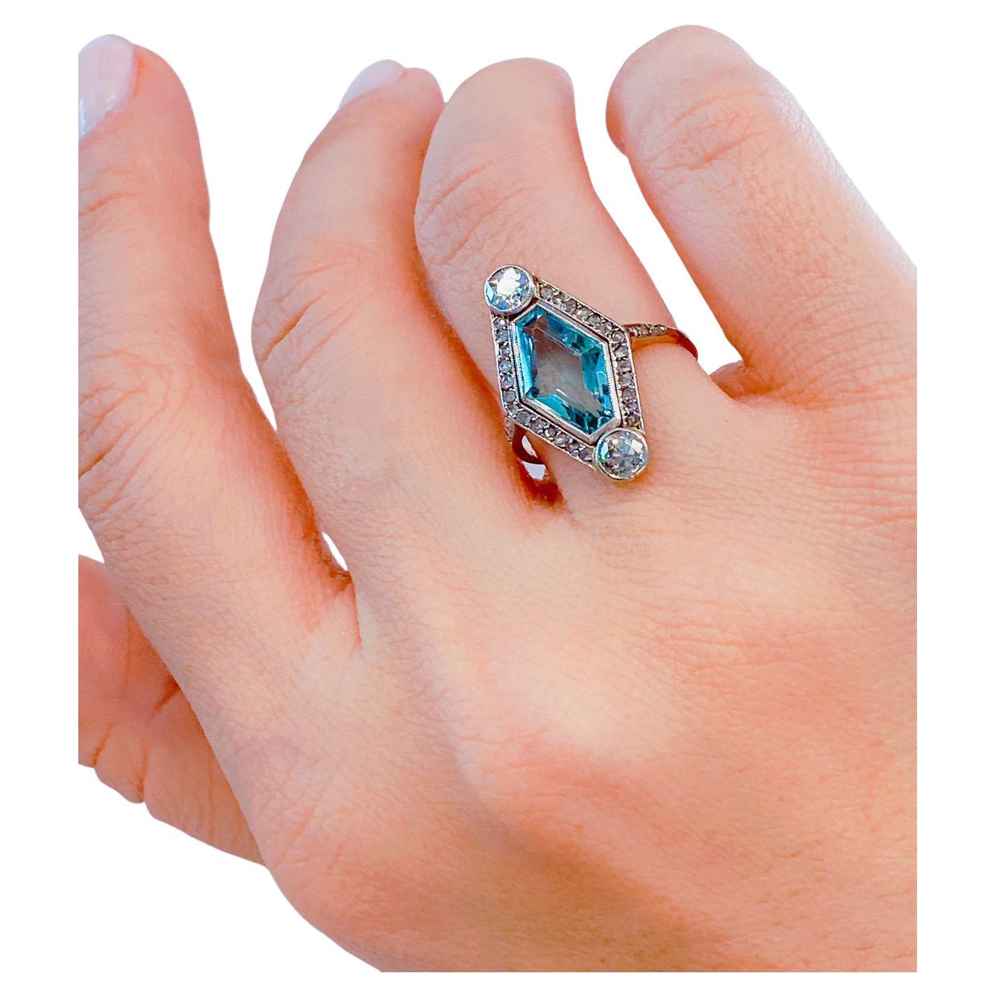 Antique ring centered with light blue aquamarine stone in octagon cut 12.22mm lenght flanked with 2 old cut diamonds estimate weight of 0.30 carats and ceveral smallers rose cut diamonds in 14k yellow and white gold in artdeco style with detailed