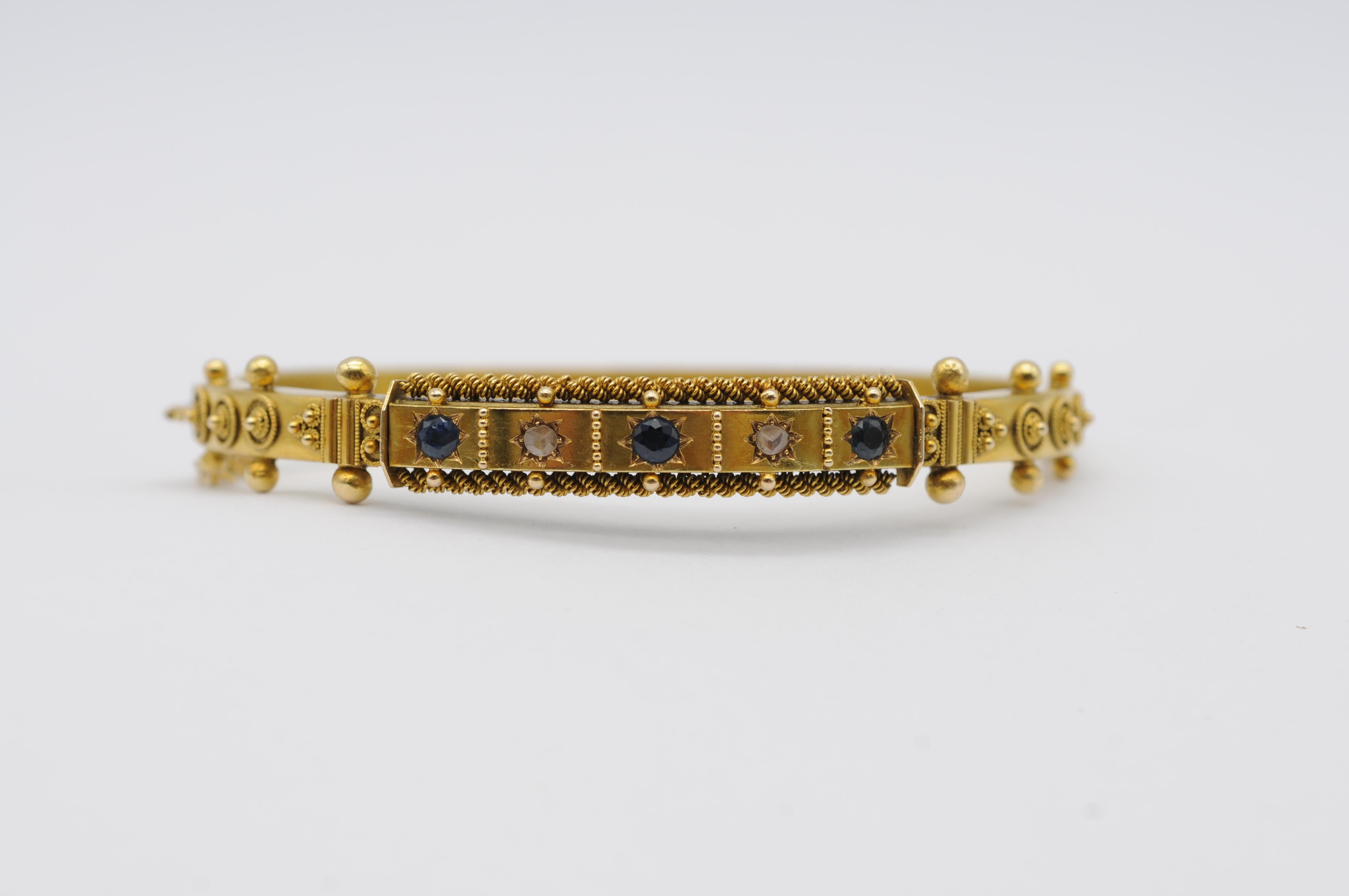 Un élégant bracelet ancien en or jaune 14 carats, au design intemporel. La pièce est ornée de deux diamants taille ancienne et de trois saphirs taille ancienne, ajoutant une touche de charme vintage à sa beauté discrète.

Le ton chaud de l'or