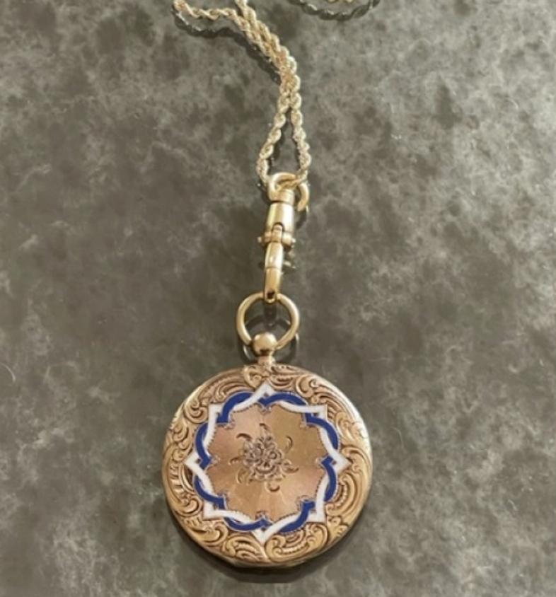 This large engraved and enameled 14k yellow gold Victorian Locket is designed in the style of a pocket watch, with a gold bail on top that swivels back and forth. The engraving is deep, intricate, detailed and elaborate with a bouquet in the center