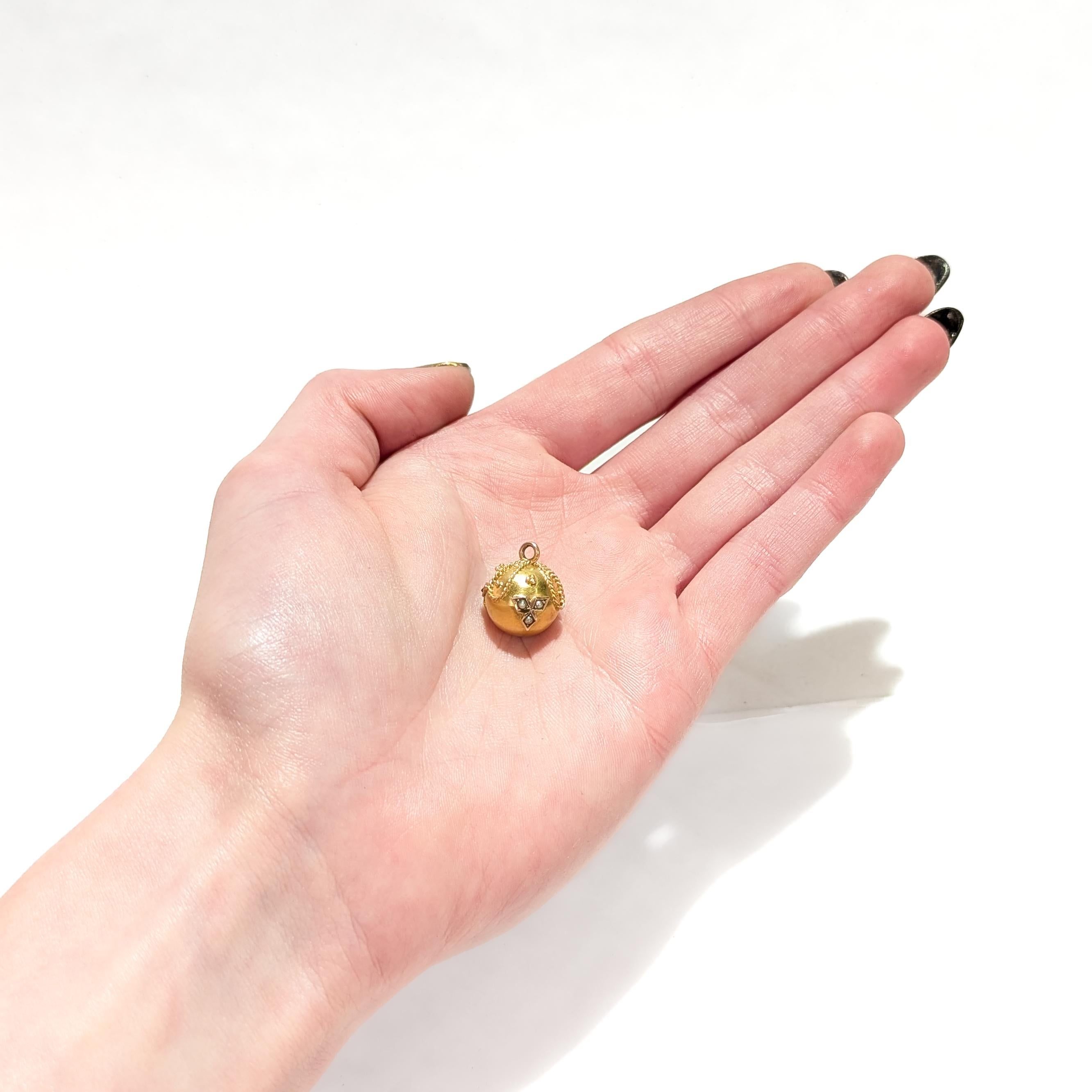 A fine Etruscan Revival ball shaped charm

In 14 karat yellow gold.

With applied wirework, granulation, and prong-set coral, and garnet & seed pearl cabochons. 

With a brushed finish throughout.

Fixed with an integral bail to the top.

Simply a