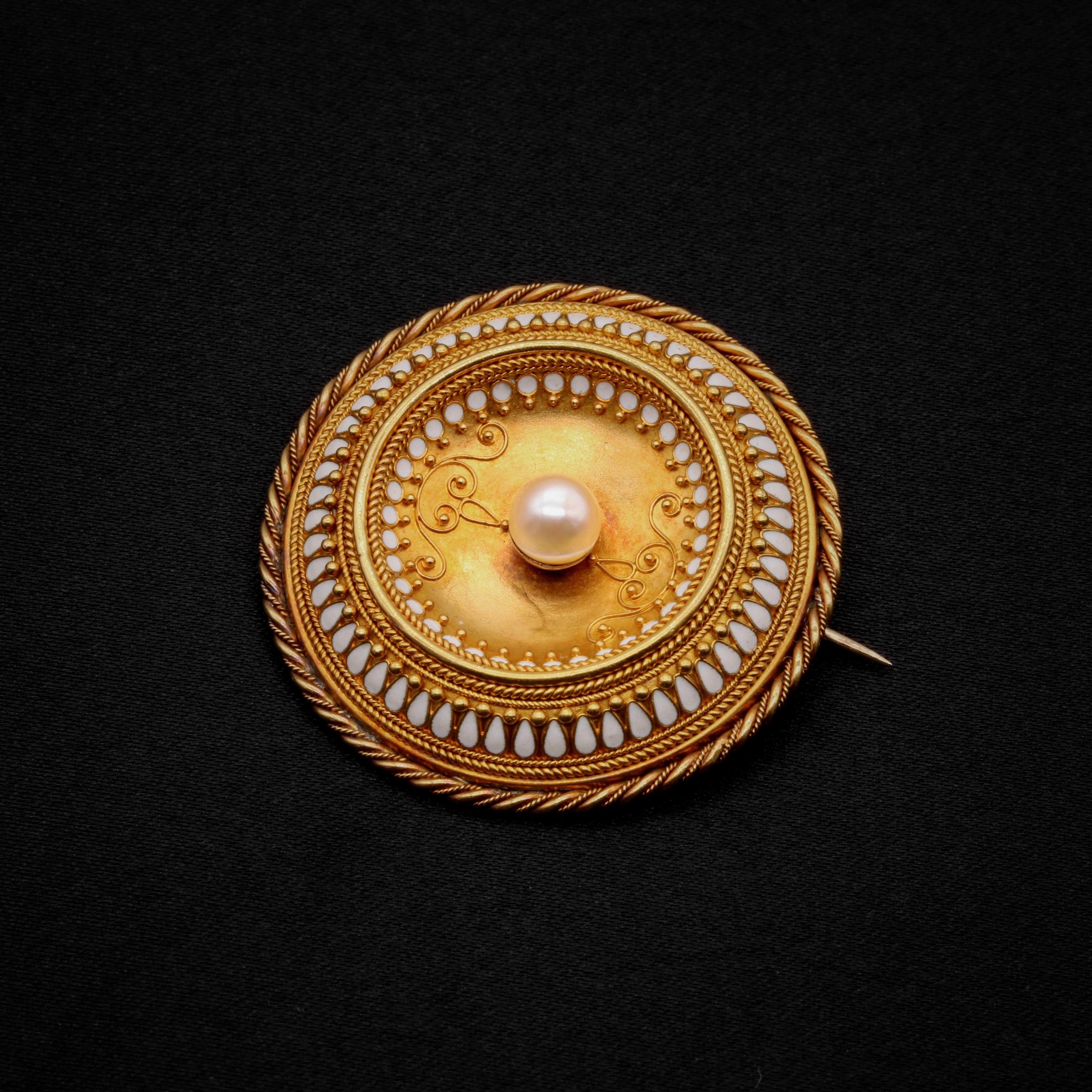 A Victorian pearl, enamel, and yellow gold brooch, comprising one round pearl, and white enamel accents, in 14 karat yellow gold. 

This outstanding Victorian brooch is set to the centre with a shimmering pearl. The pearl is pale and lustrous. The