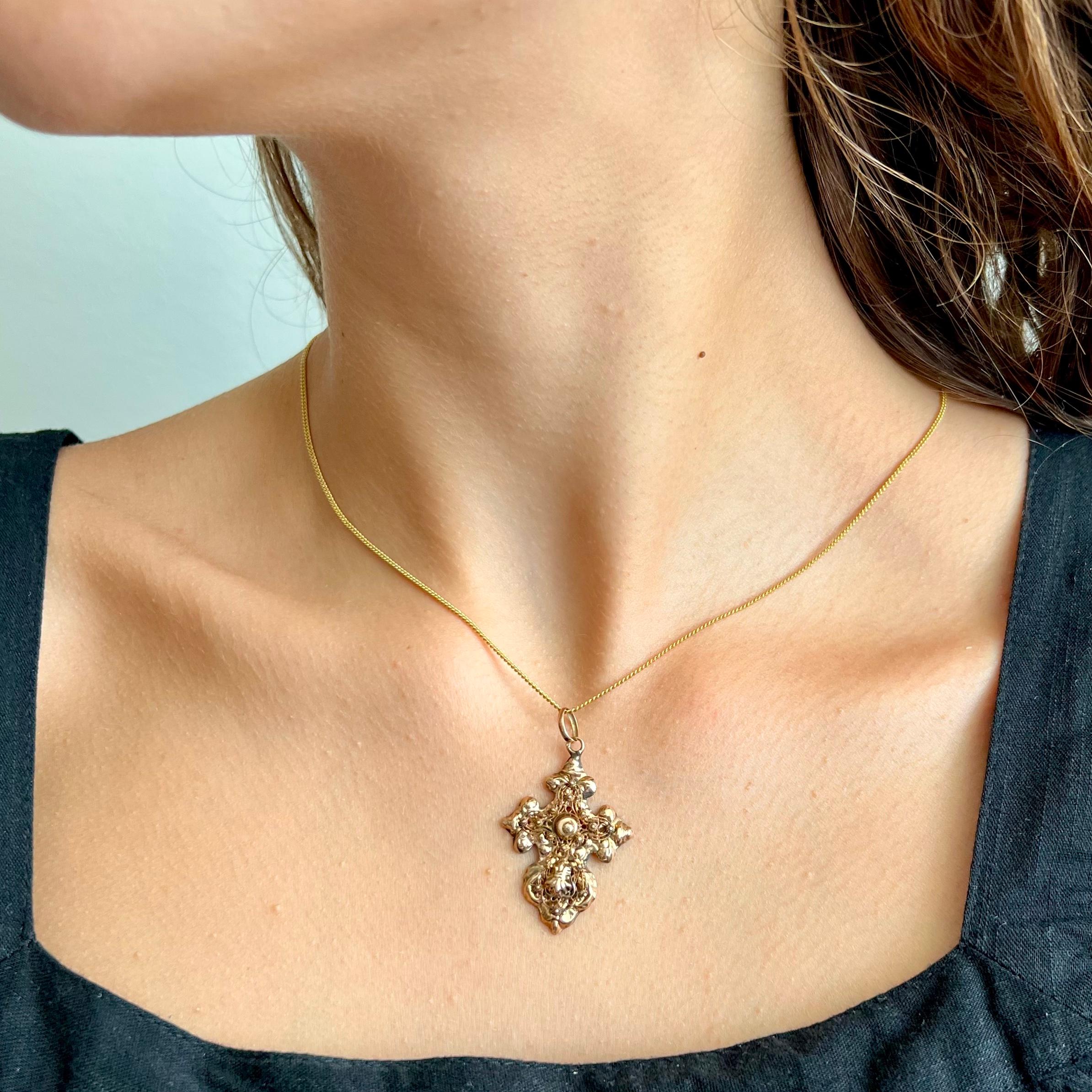 An antique 19th century Dutch cross pendant created with fine wire and cannetille work. This lovely antique cross is beautifully decorated with a repoussé design throughout the cross, a technique of metalworking in which the gold is shaped by